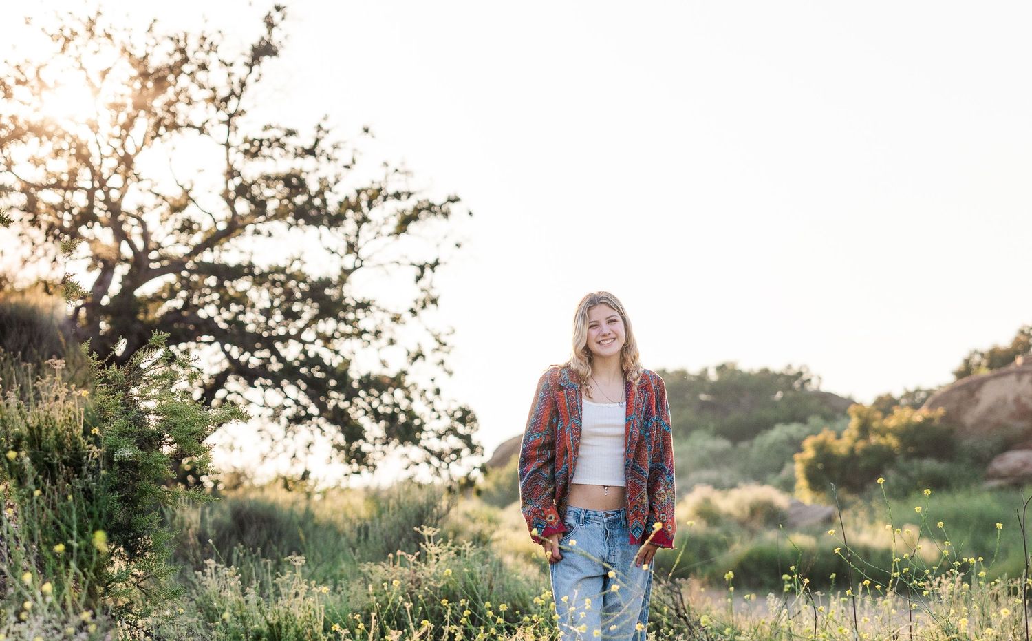 Natural sunset portrait in denim and plaid jacket among wildflowers.