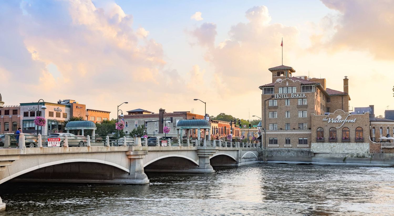 A scenic view of downtown St. Charles, Illinois, showcasing the historic architecture along the Fox River. The riverwalk