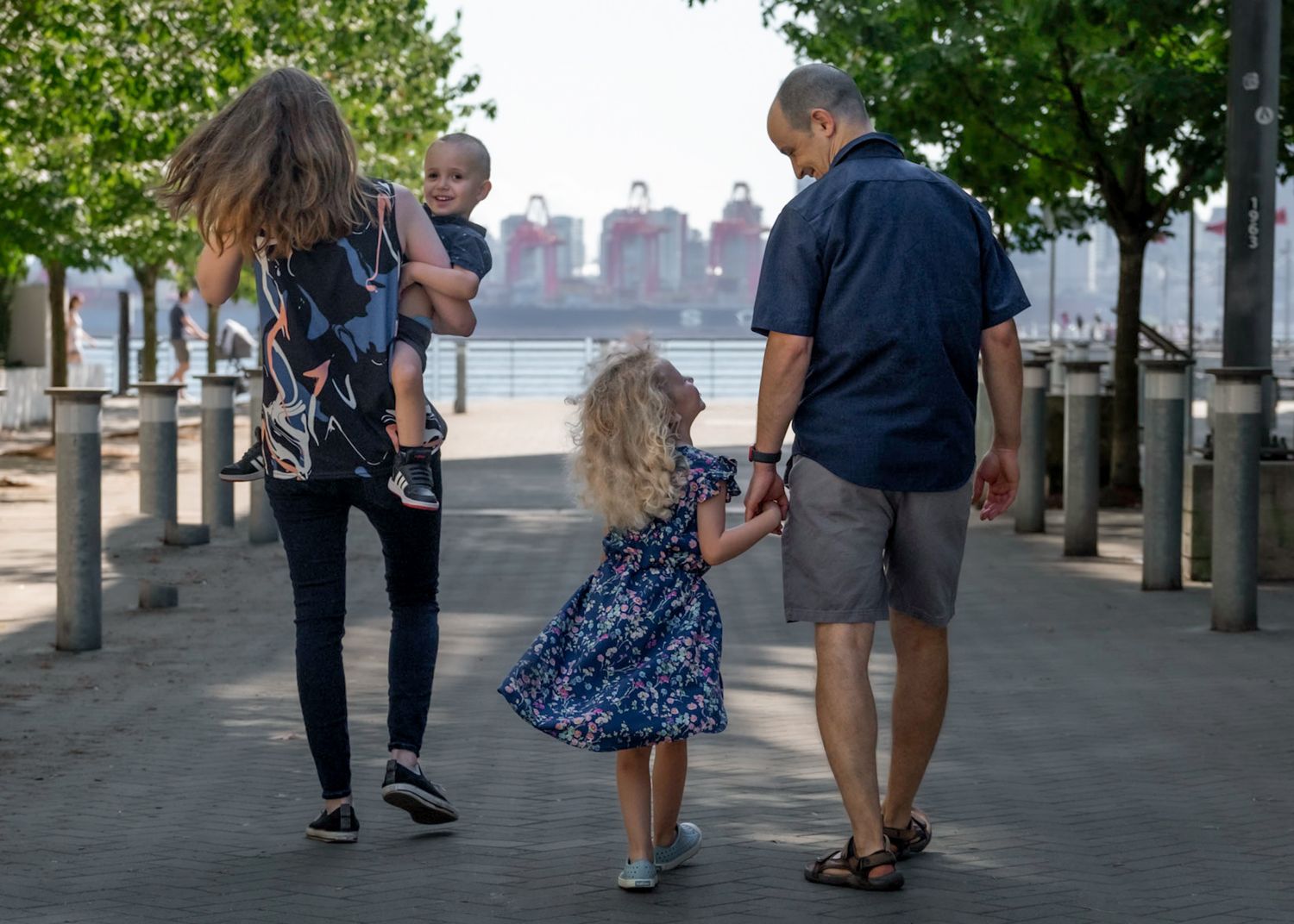 Family of four laughing during fun natural summer lifestyle family photo session at North Vancouver’s Shipyards district