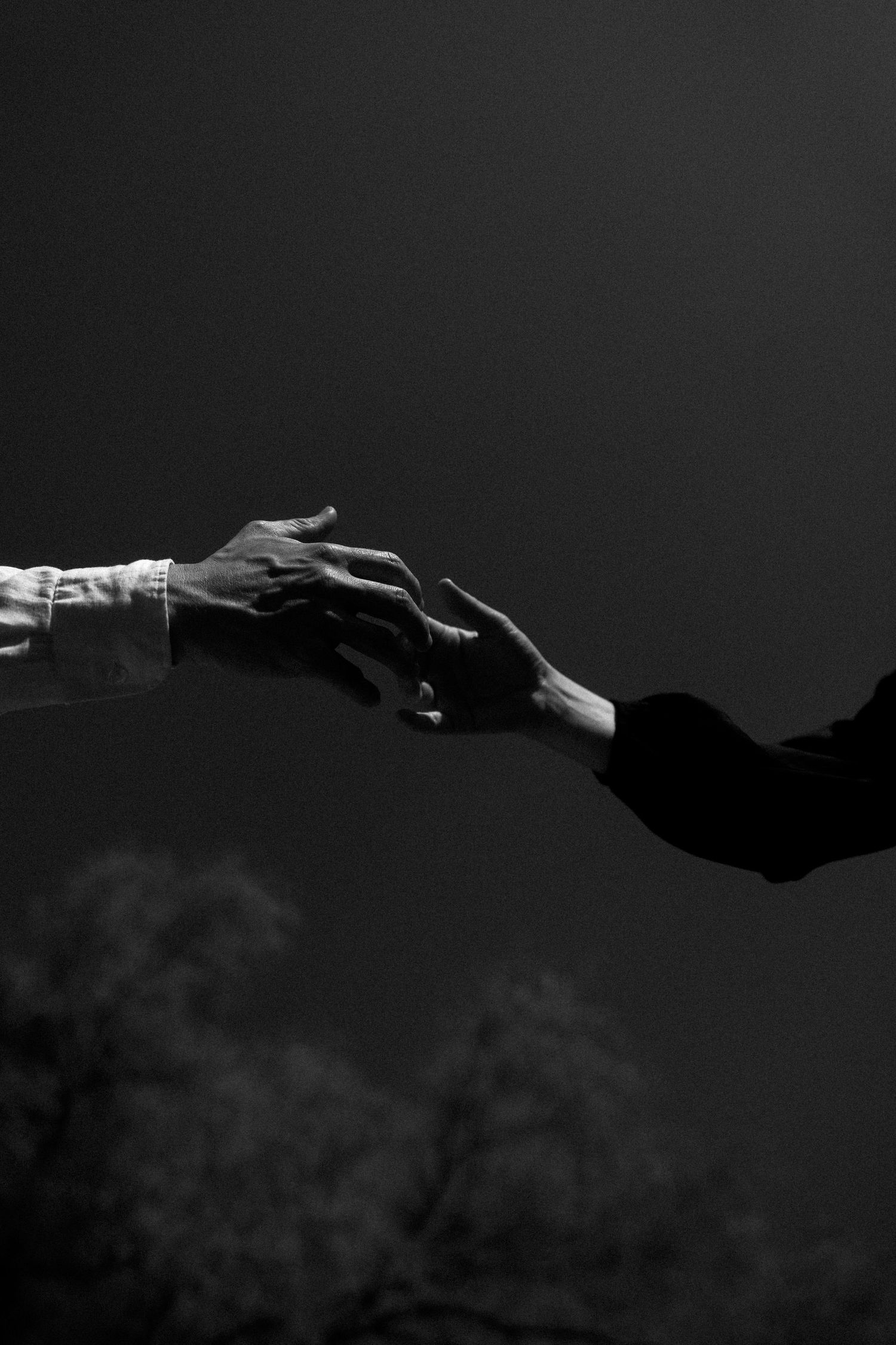A dark silhouette of mountain peaks against a black and white sky with dramatic shadows and contrast.