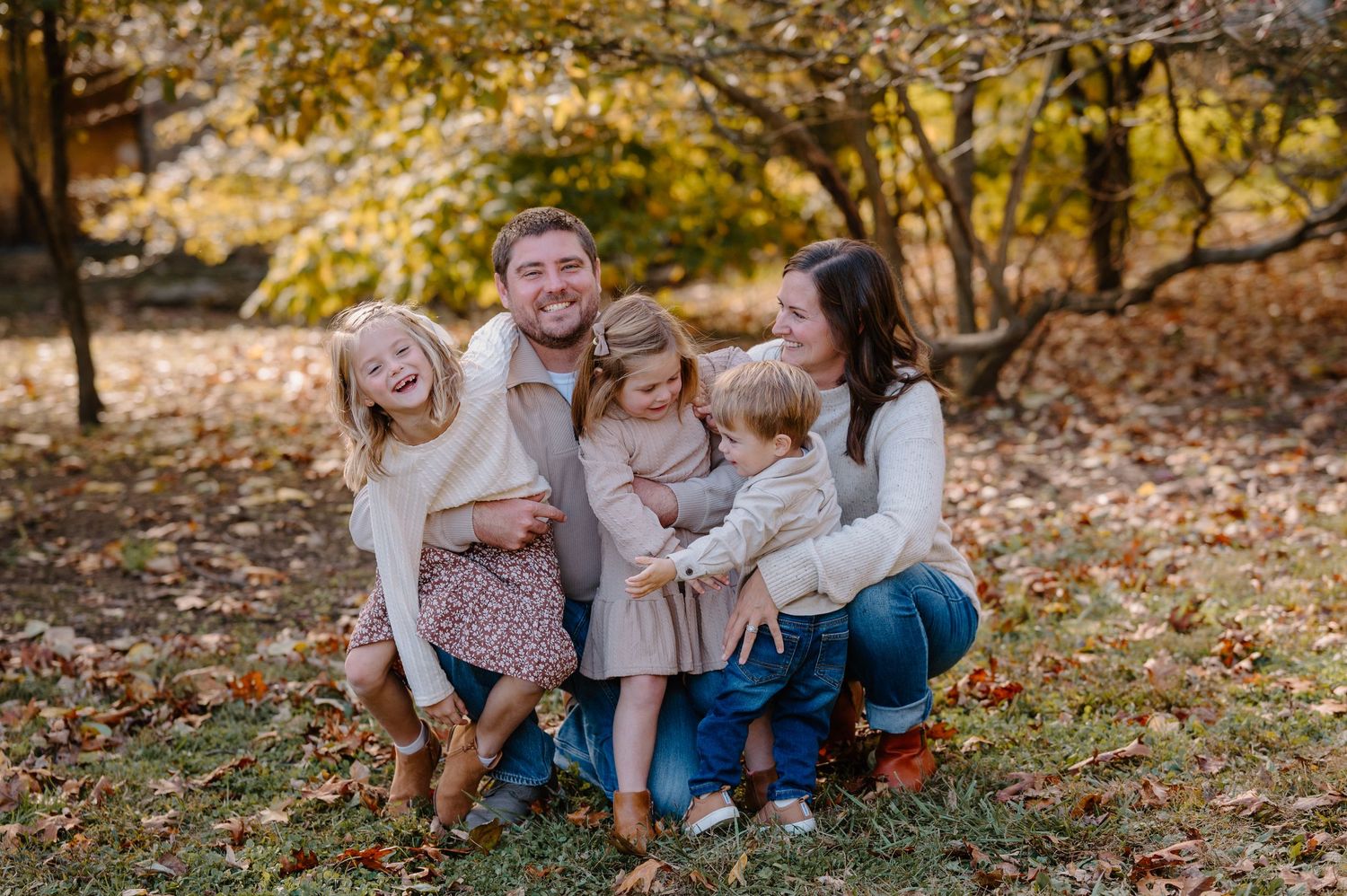 Happy family of five smiling together outdoors in autumn park with colorful fall foliage background.