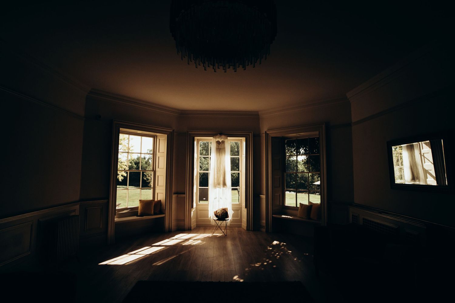 Dark moody interior room with dramatic window light casting shadows on empty walls and floors.