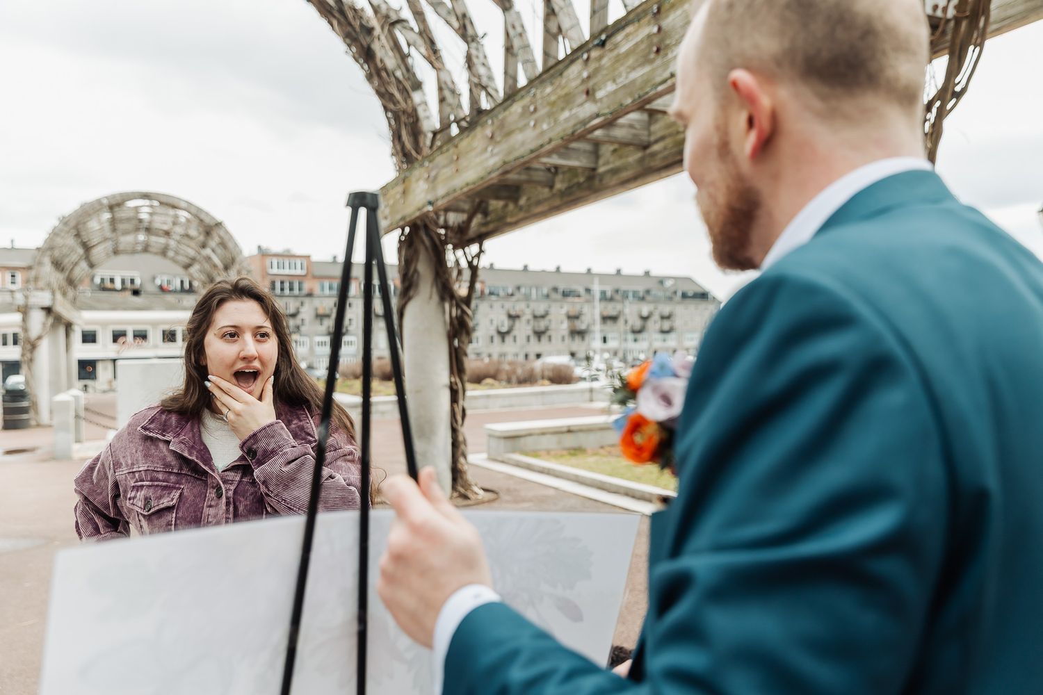 Couple poses with dog in wedding attire before Boston skyline and Custom House Tower.