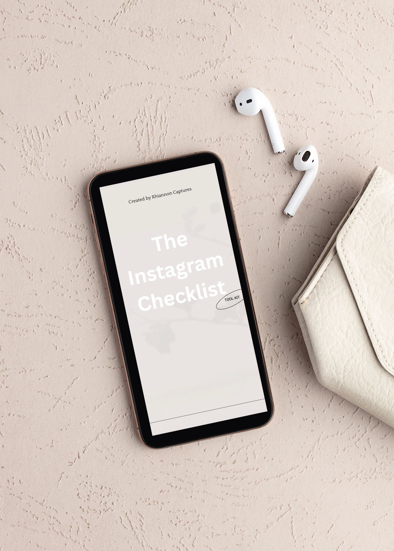 Smartphone displaying Instagram checklist beside AirPods and white wallet on beige textured surface.