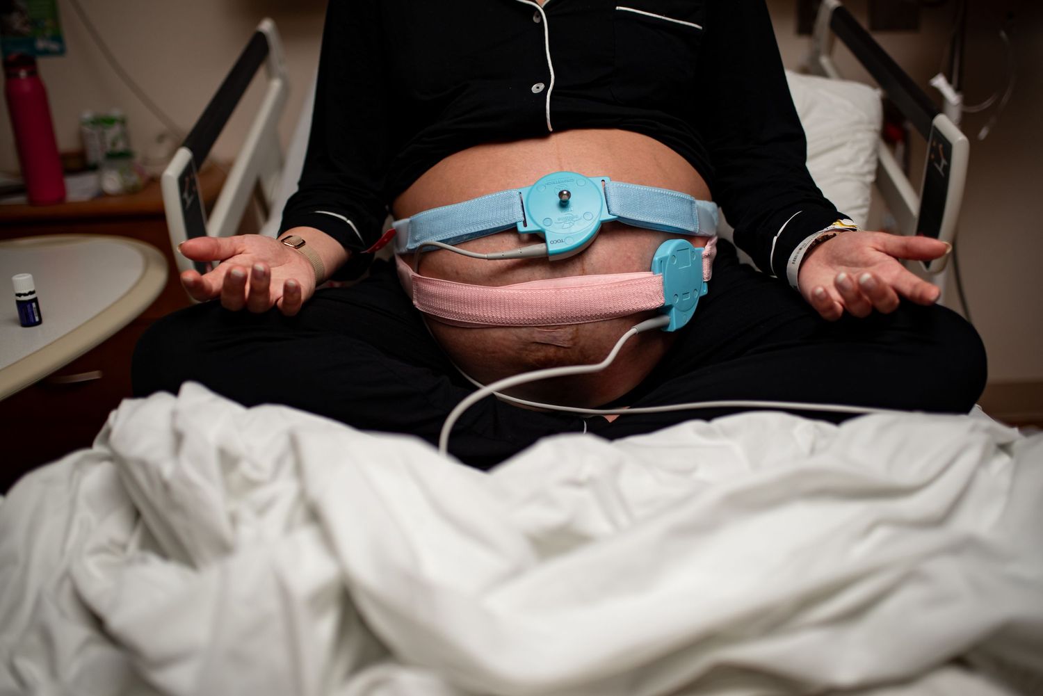 Medical professional in protective gear performs ultrasound examination on patient lying on hospital bed.