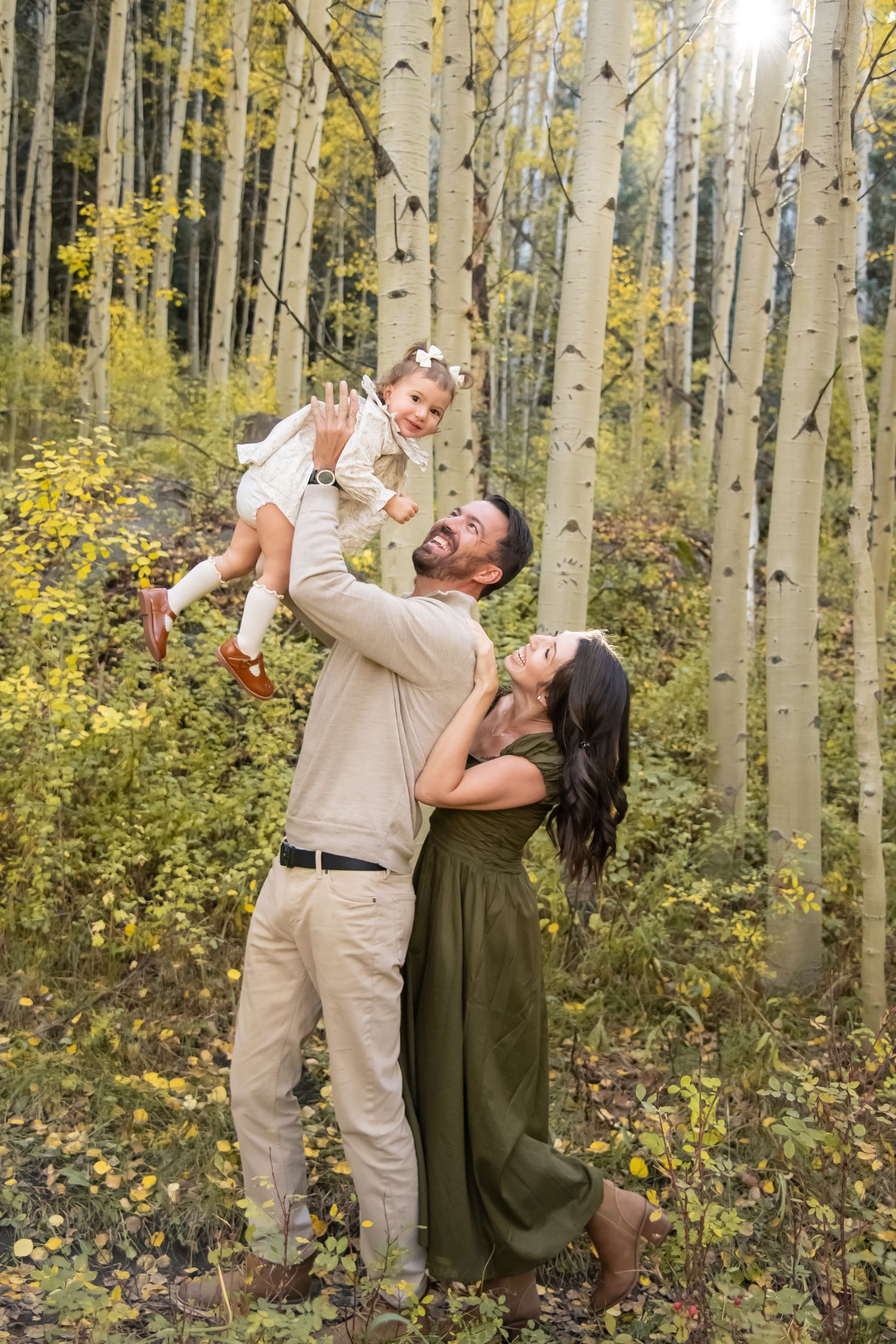 Playful couple poses in autumn aspen grove with falling yellow leaves.