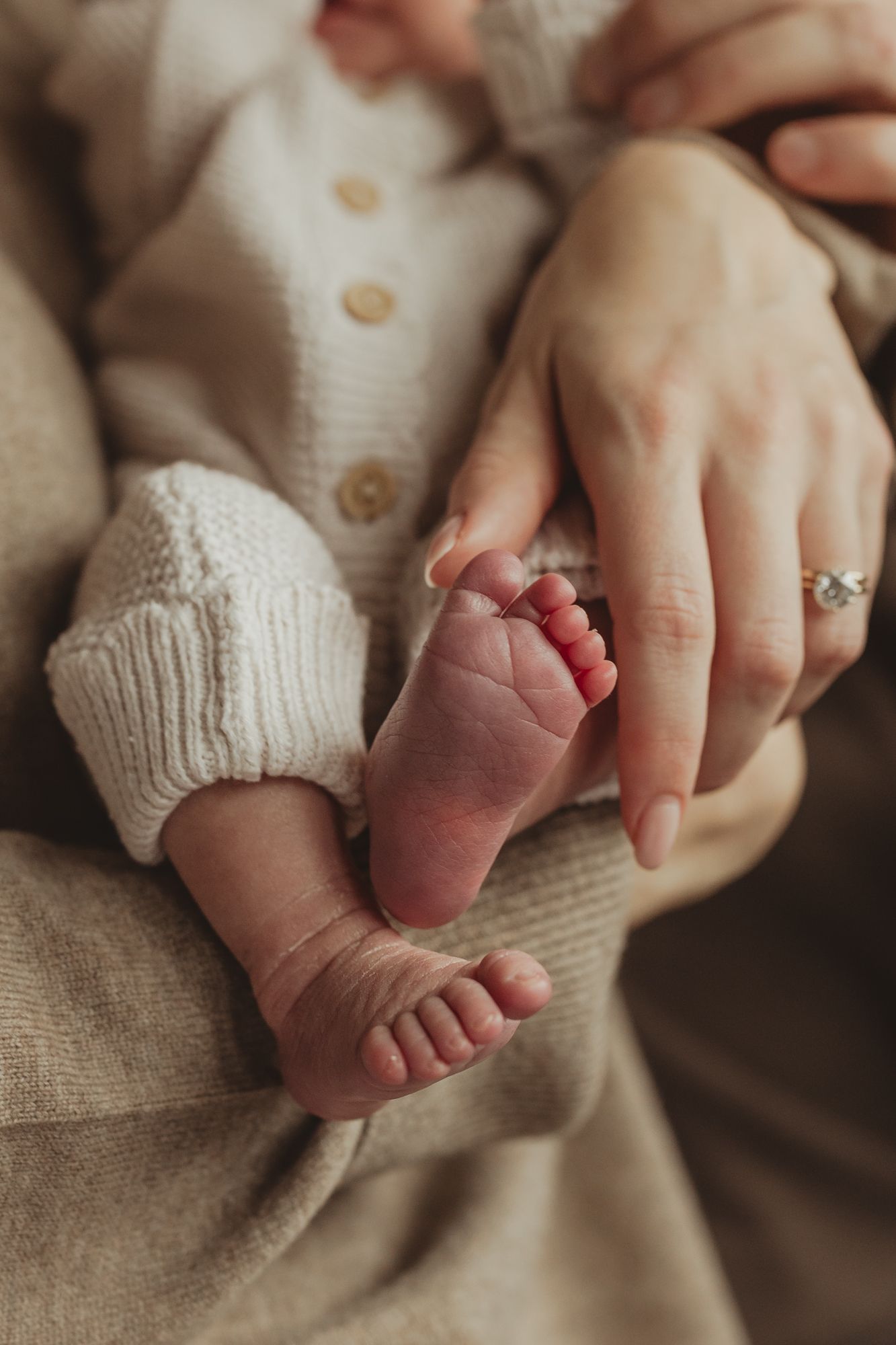 Close-up photo series showing tiny newborn baby feet being gently held by adult hands against a neutral beige background.