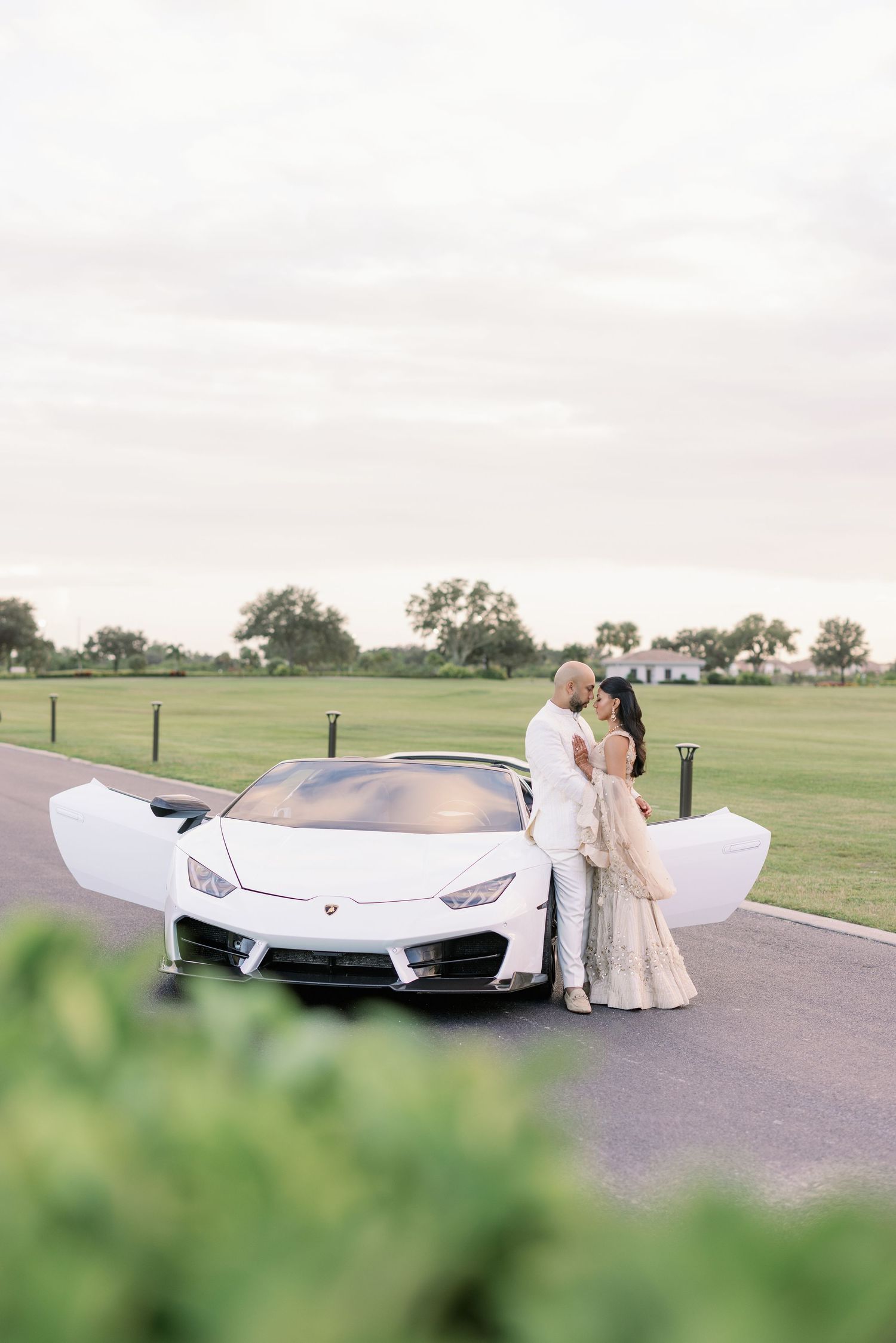 A romantic couple in white outfits share an intimate dance moment at sunset in an outdoor setting.