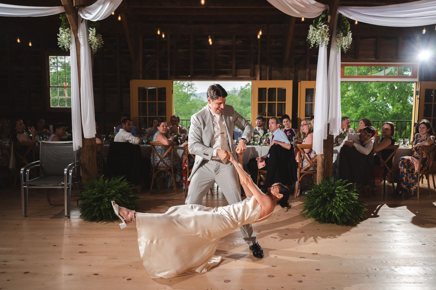 Groom dips bride in first dance under elegant white fabric draping at rustic wedding reception at The Ruins at Sassafras in New Lebanon, NY.