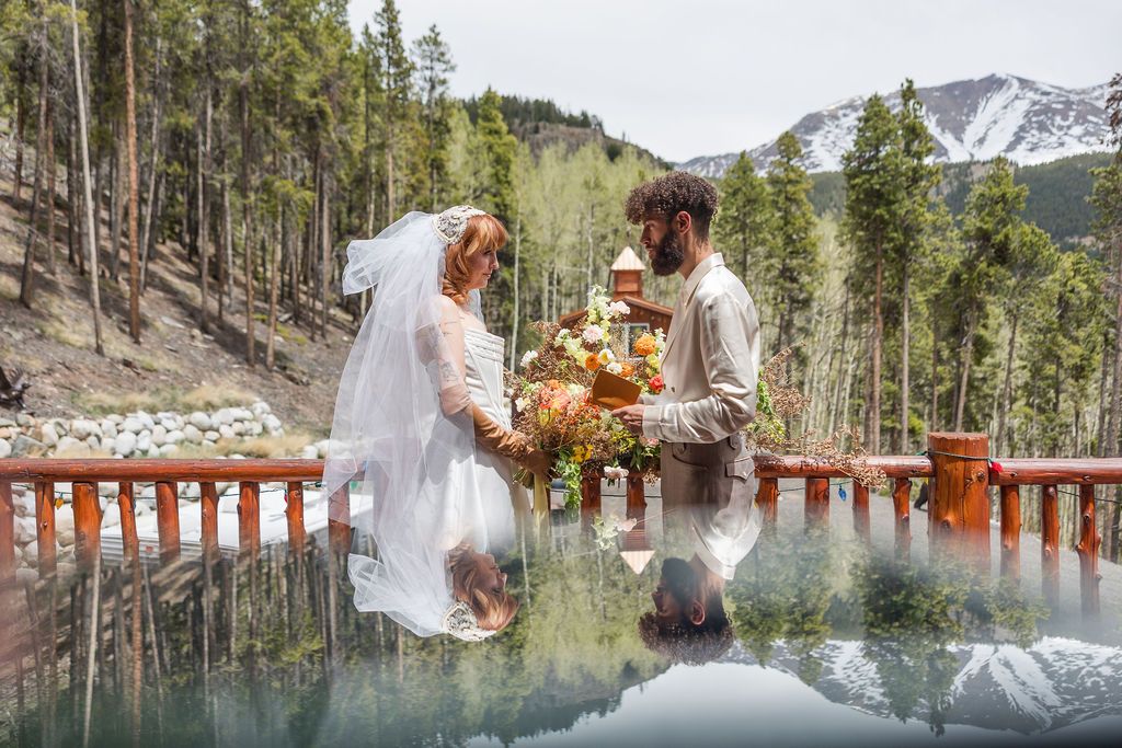 Rustic mountain wedding ceremony with pine trees and snow-capped peaks in the background creates a romantic outdoor scene.