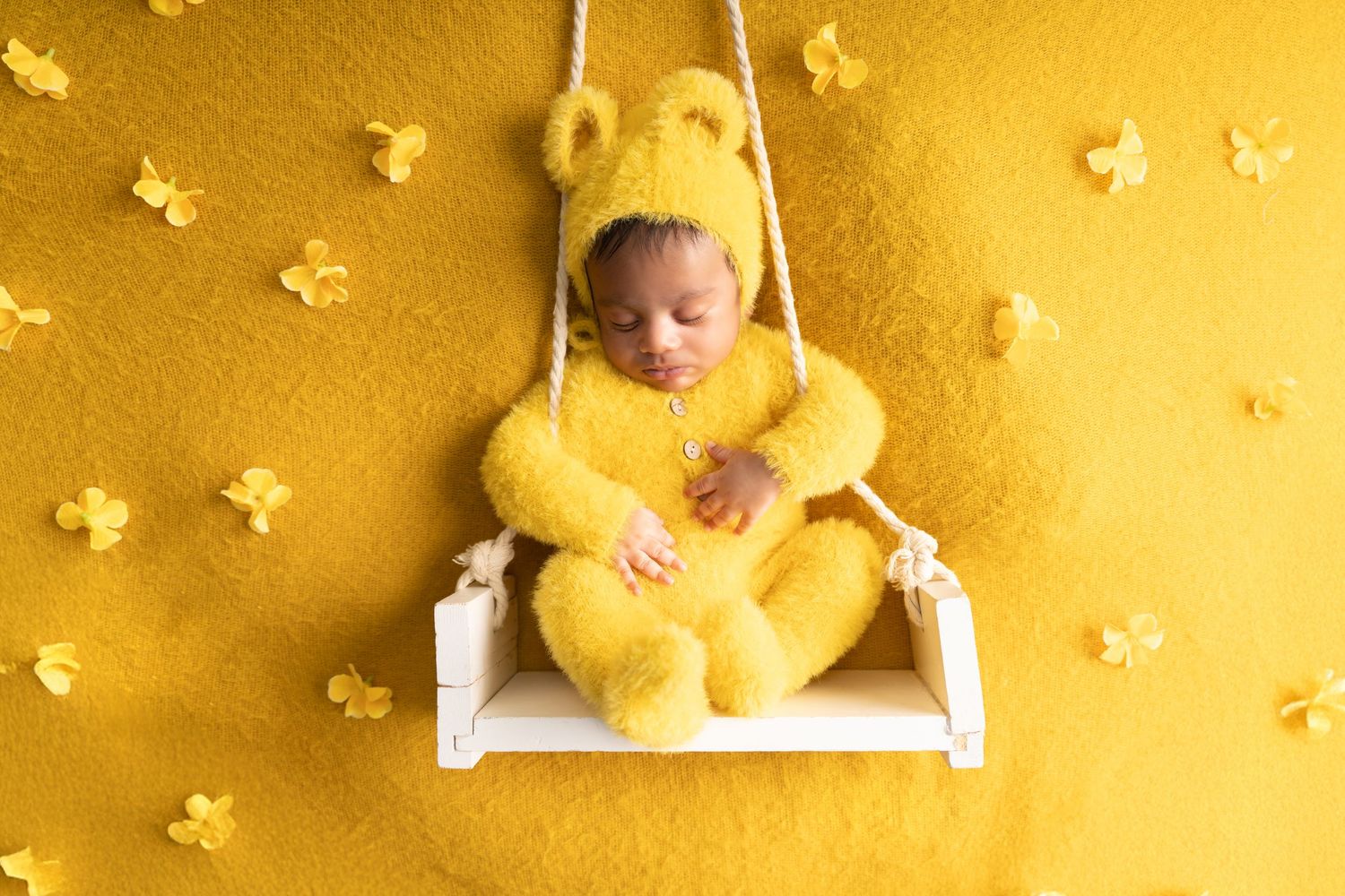 Yellow teddy bears and small butterflies create a whimsical scene on a golden background.