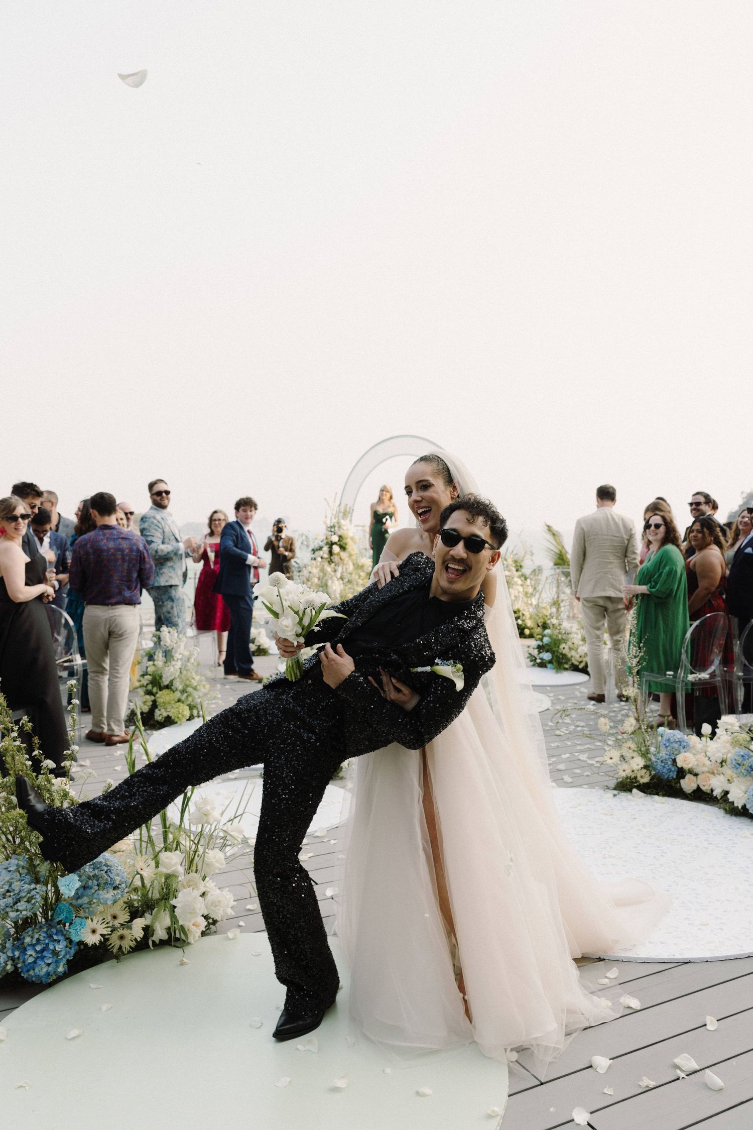Person wearing all black performs martial arts poses at a formal wedding reception with floral decorations.