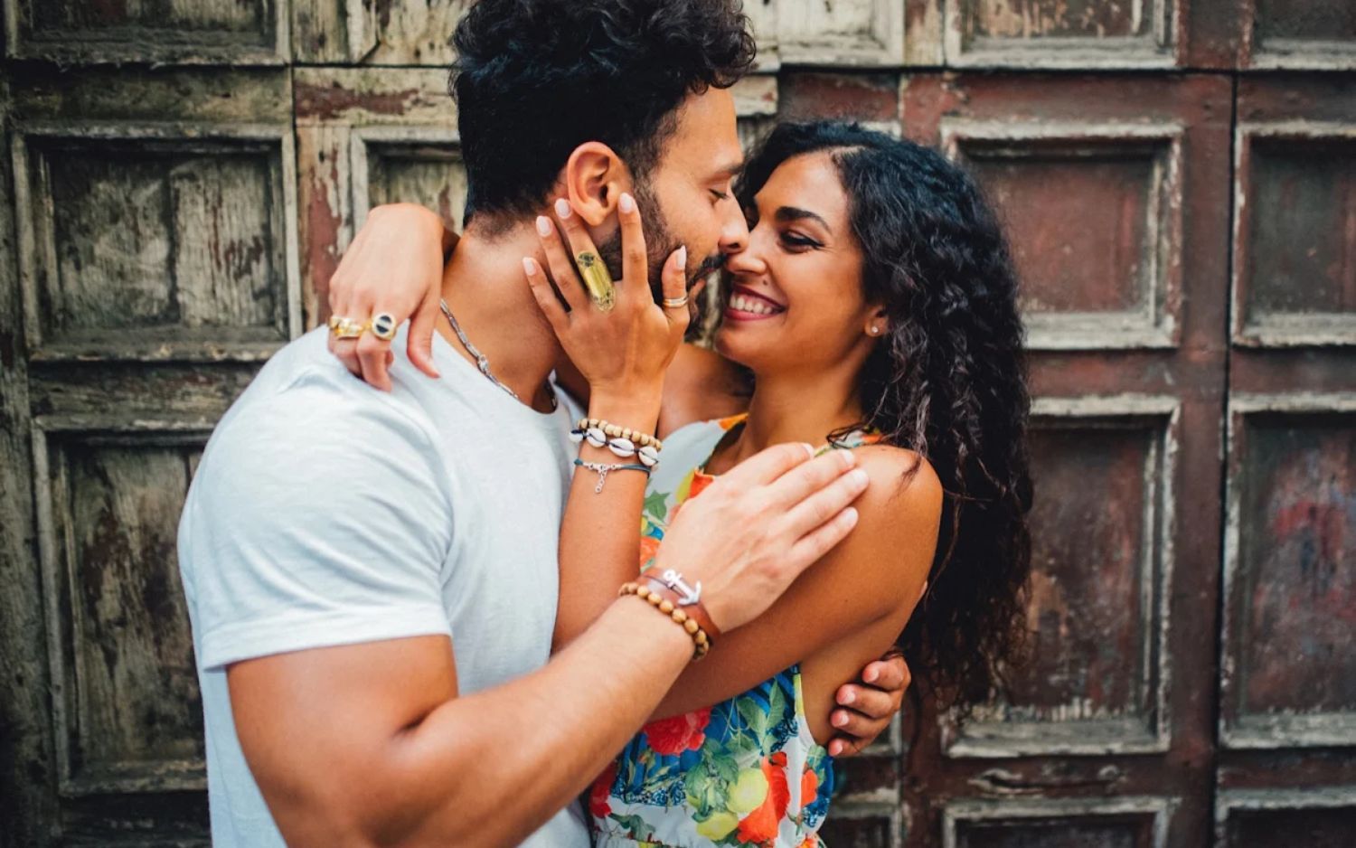 A couple shares tender moments together in a romantic photo collage against a rustic wooden backdrop.