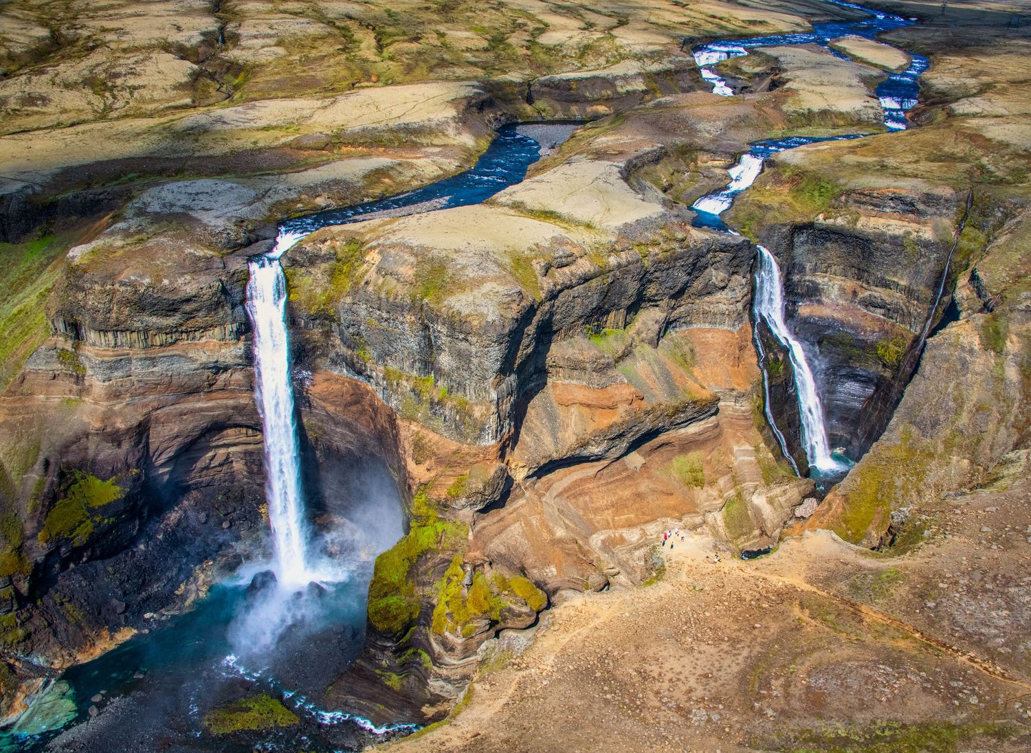 Aerial view of multiple waterfalls cascading down rocky cliffs in a dramatic landscape.