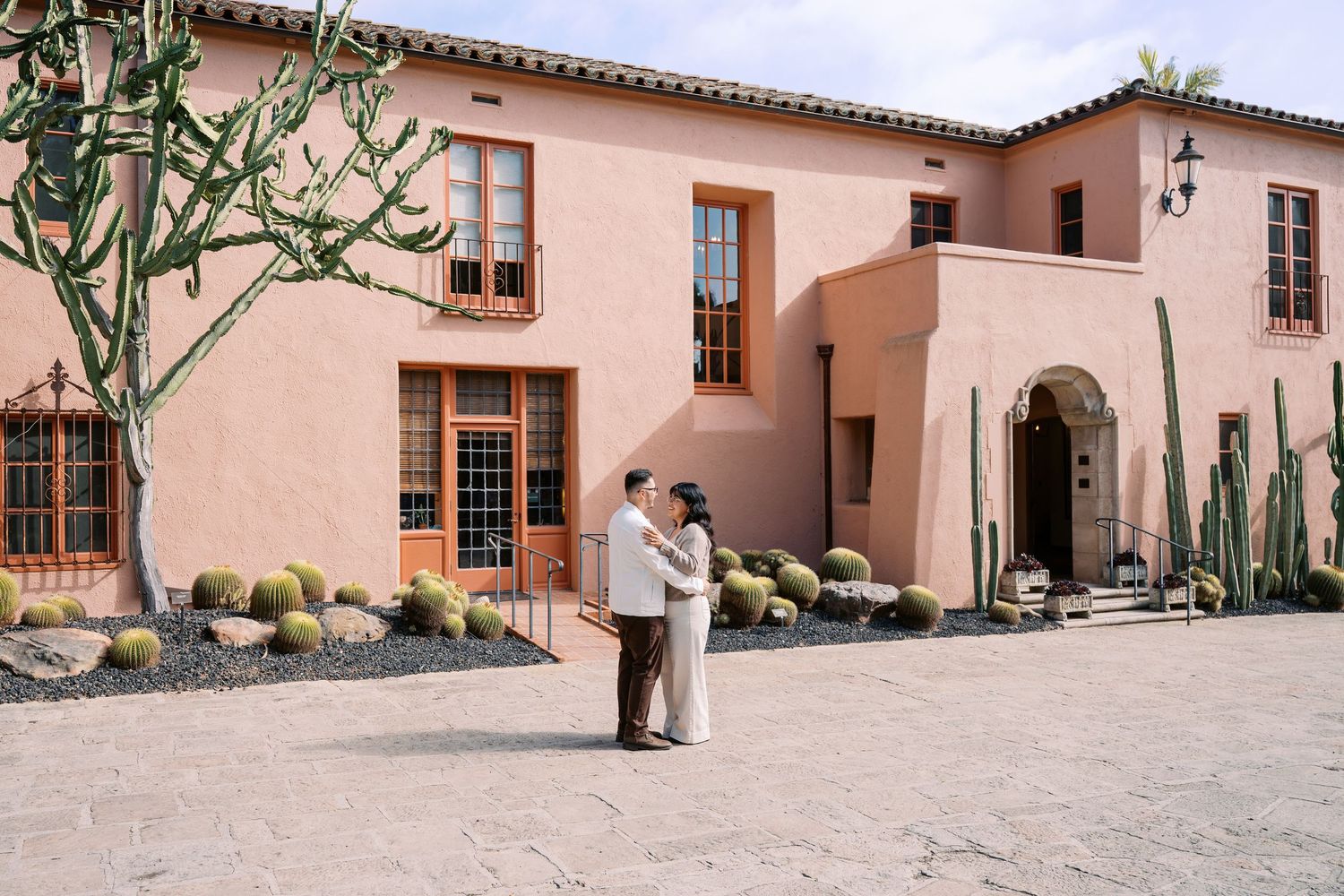 Panoramic view of a Spanish colonial style building with peach stucco walls and terracotta roof tiles in the desert.