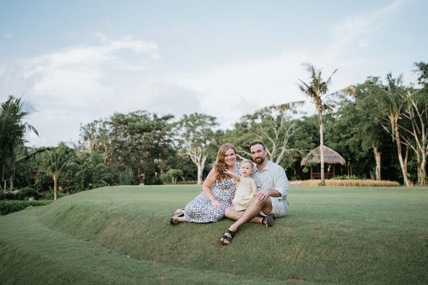 Family enjoying a sunset photoshoot in a lush tropical garden setting.