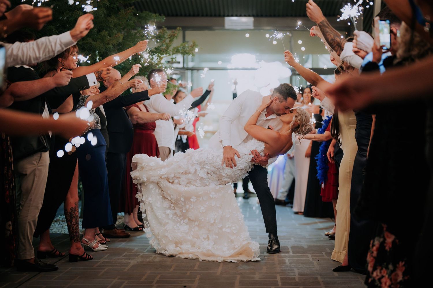 Wedding exit celebration with guests creating sparkler tunnel for dancing couple.