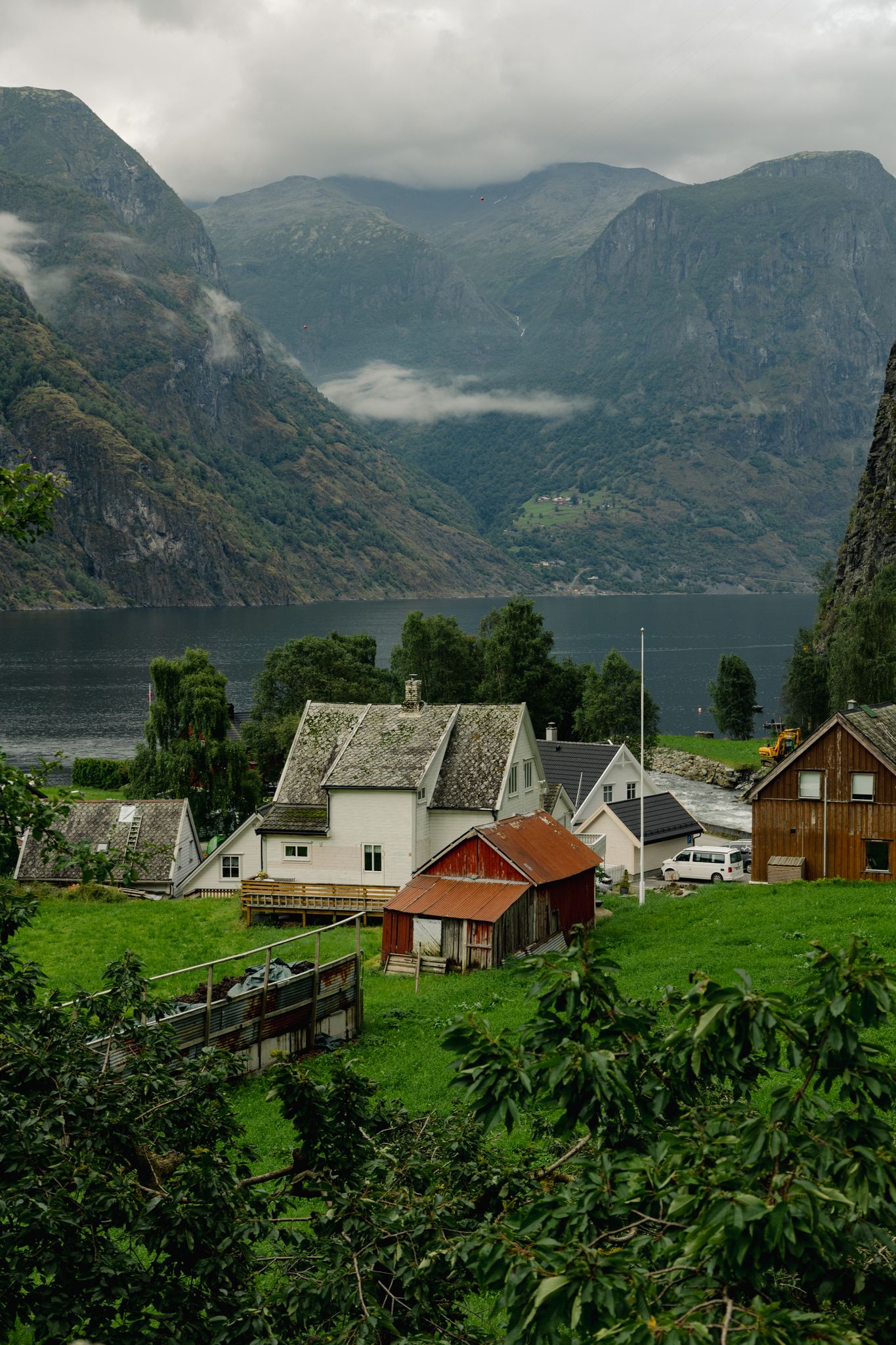 Scenic Norwegian fjord landscape with colorful wooden houses nestled along the waterfront beneath misty mountain peaks.
