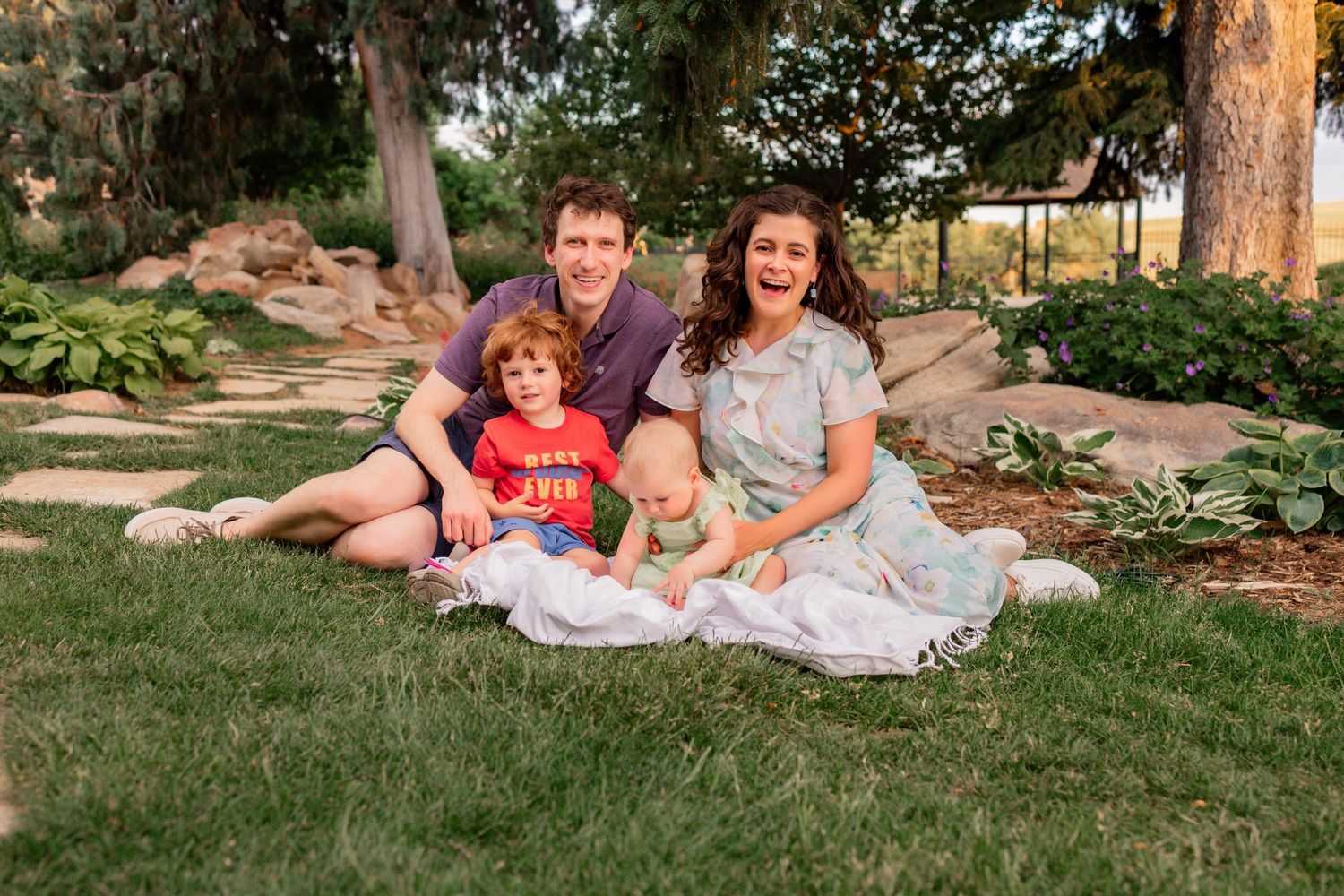 Family of four sat outside on a blanket on the grass, golden hour photoshoot