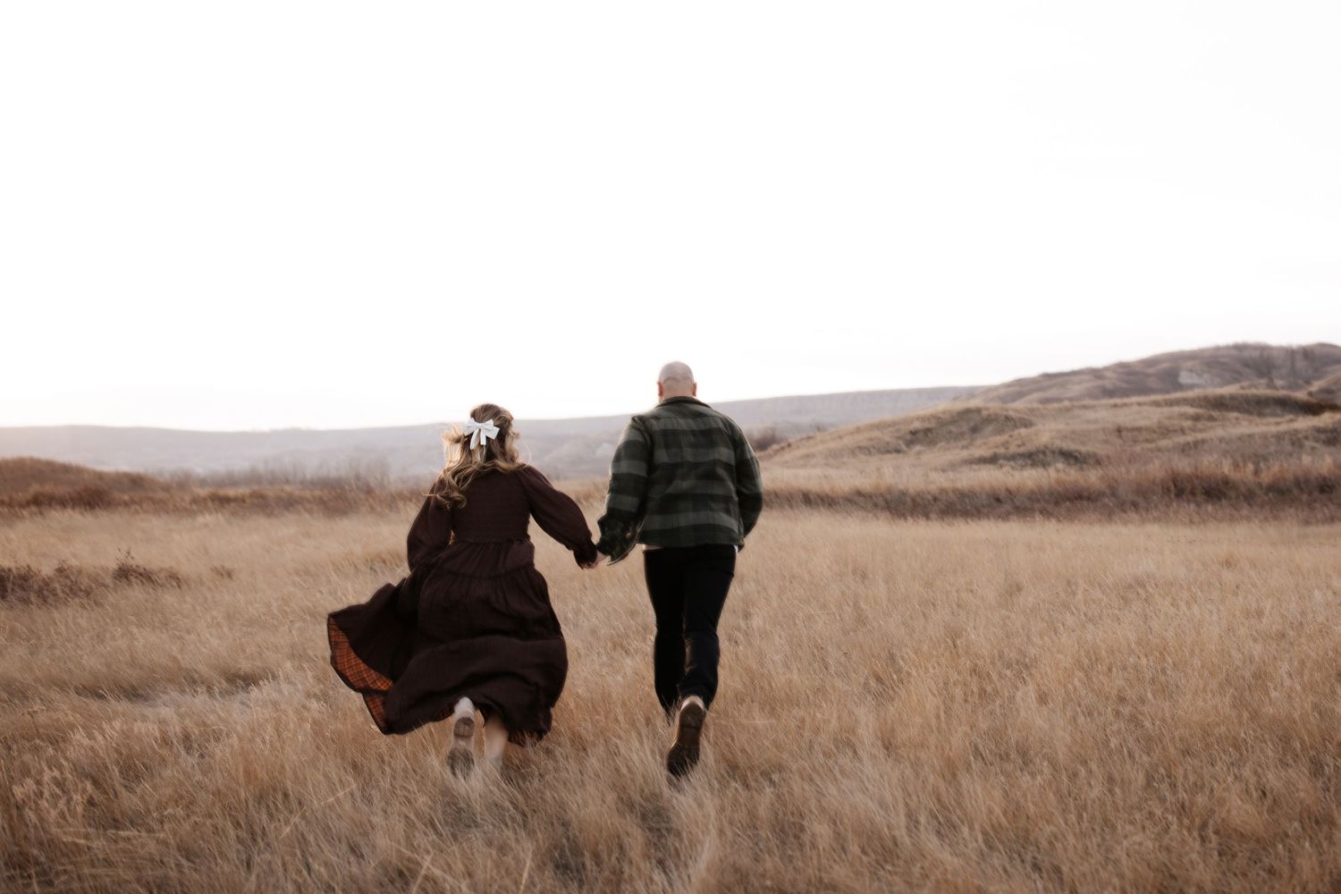 Silhouettes of a couple walking through golden grass at sunset.