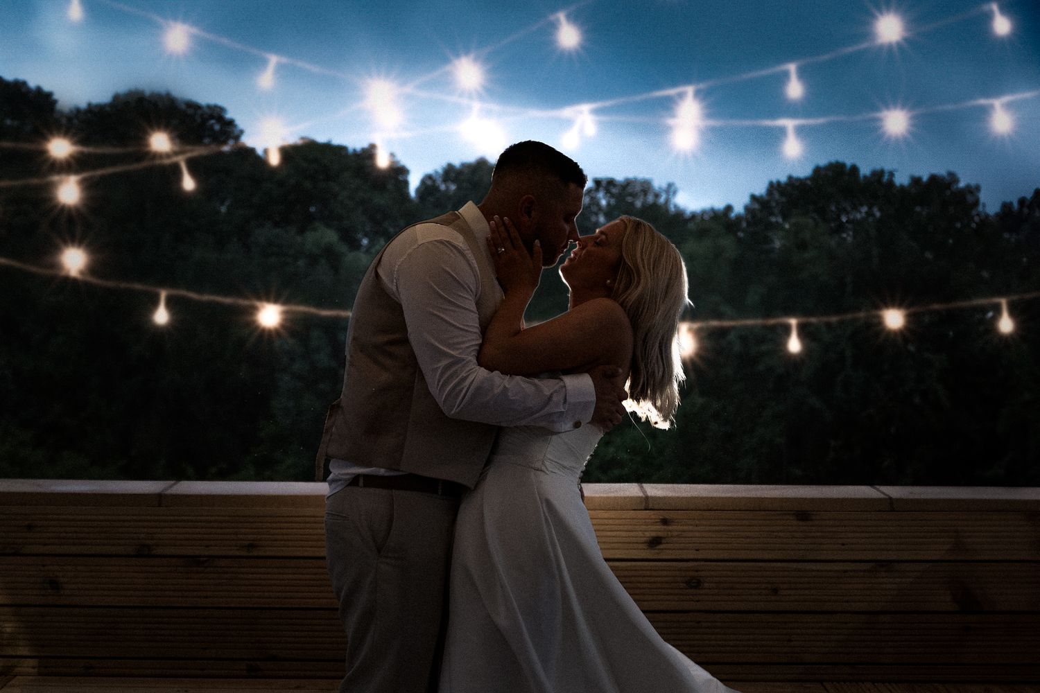 Romantic evening dance under string lights on outdoor deck.