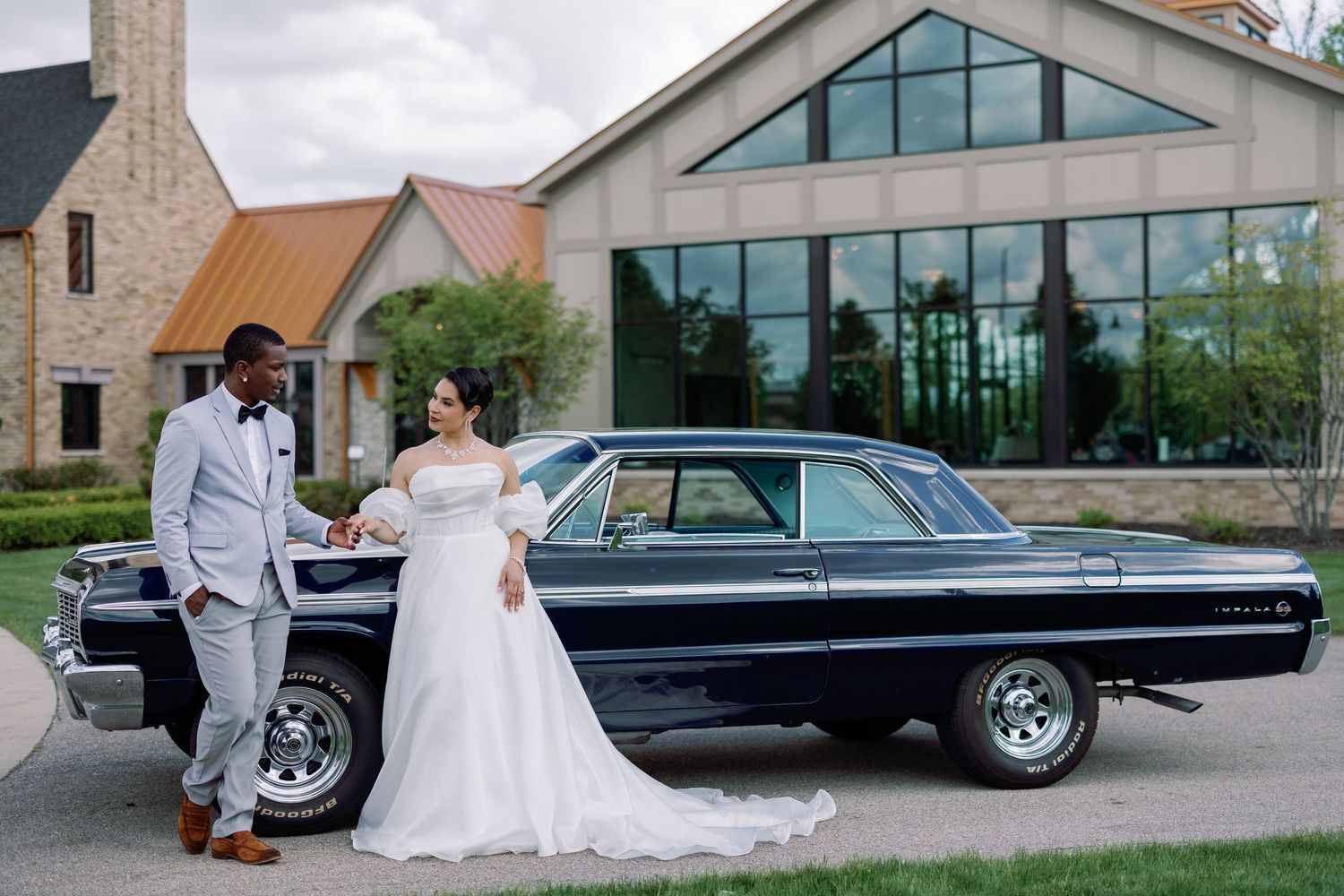 A classic white Volkswagen Beetle serves as a wedding photo backdrop with a couple posing next to the vintage car at Venue 3Two.