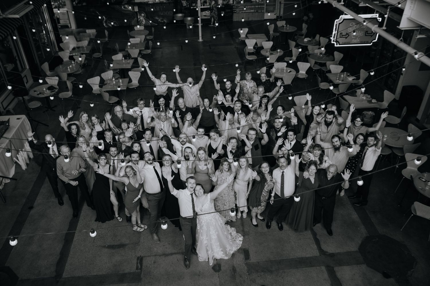 Black and white aerial shot of a wedding reception with a large crowd celebrating on the dance floor at a venue.