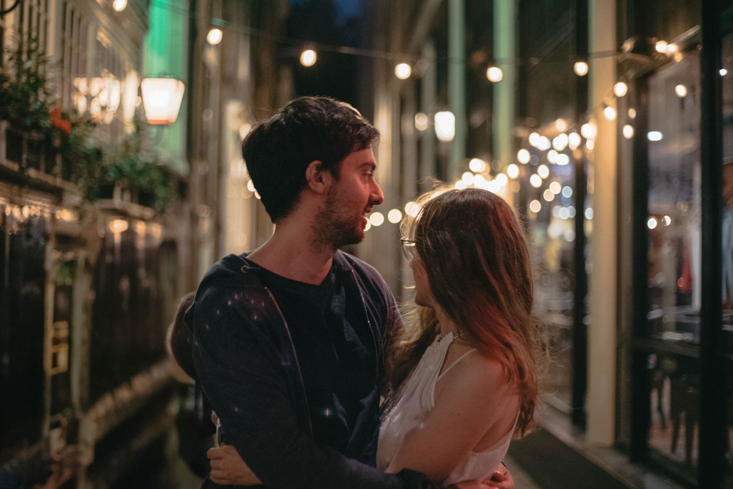 Romantic couple embracing in dimly lit Amsterdam narrow street.