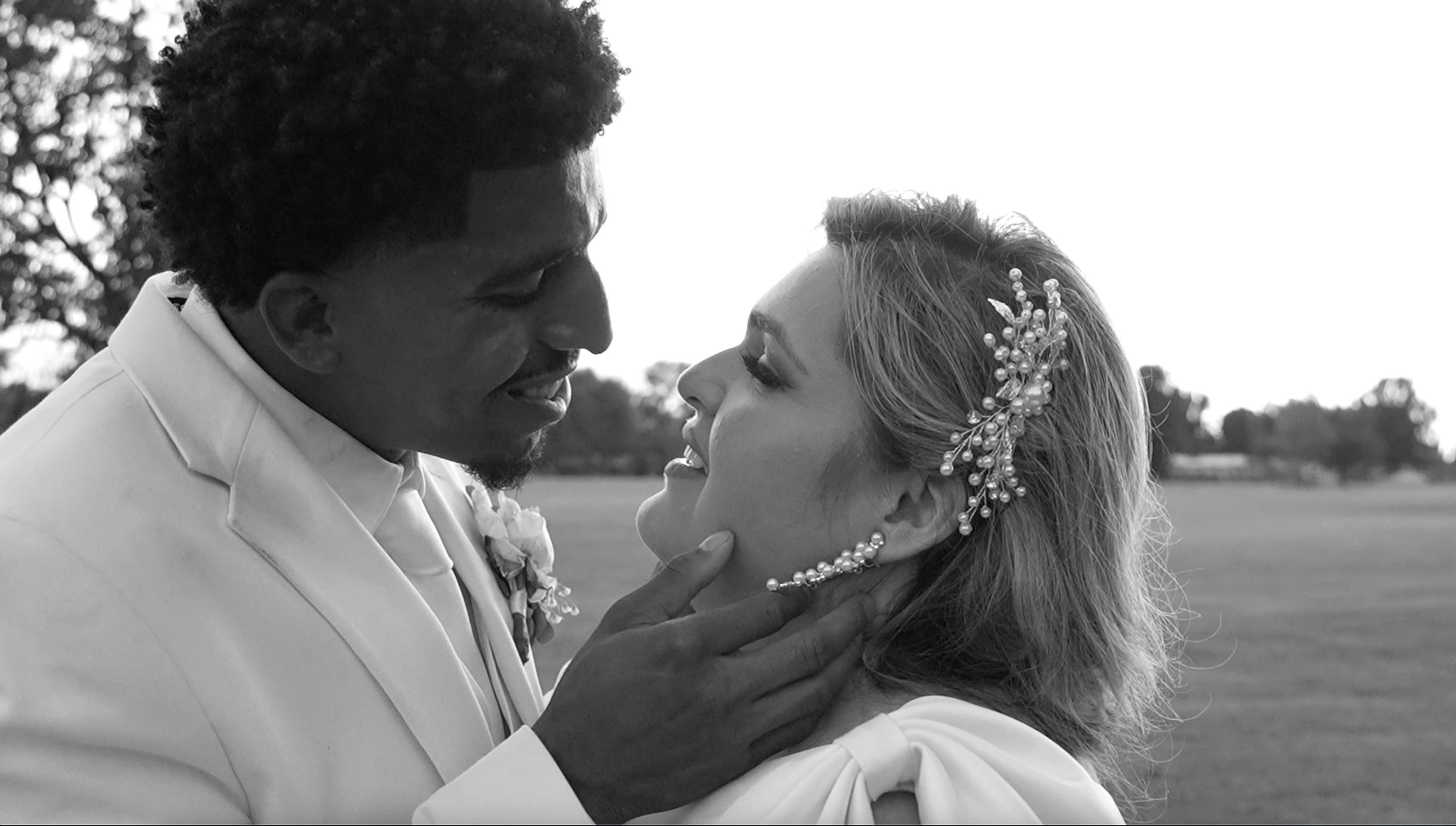 Black and white romantic portrait of newlyweds sharing an intimate moment outdoors.