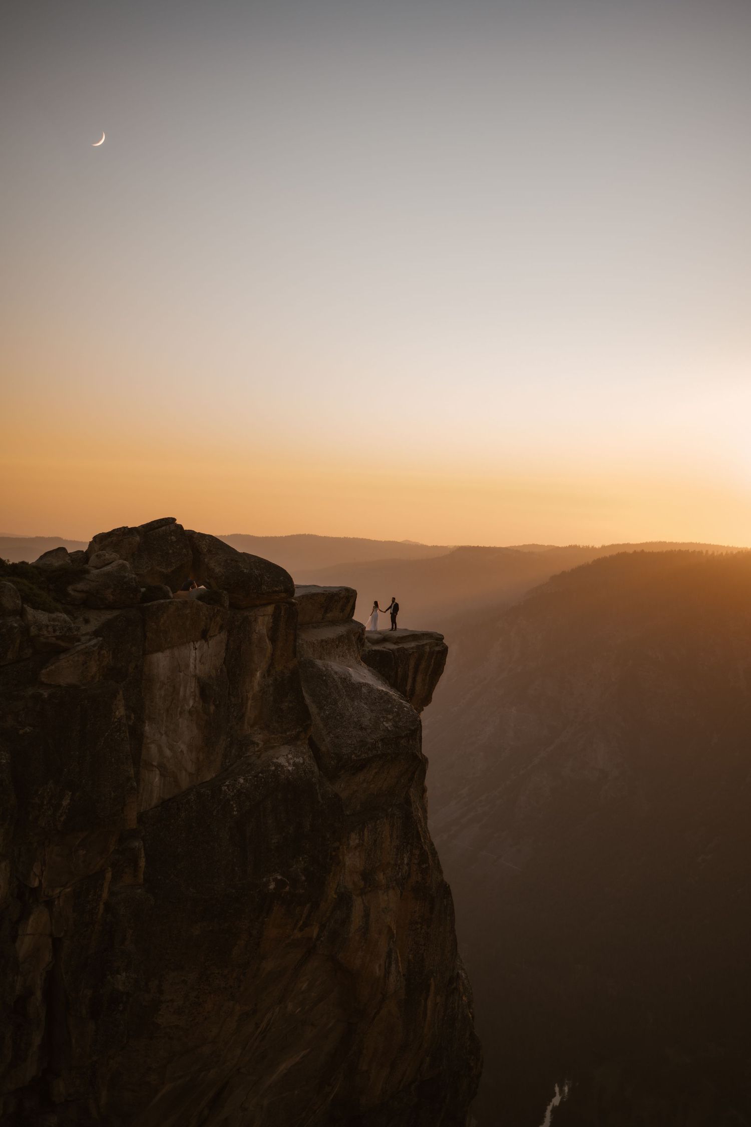 Dramatic sunset view of towering cliffs at Yosemite's Taft Point with silhouettes against the golden sky.