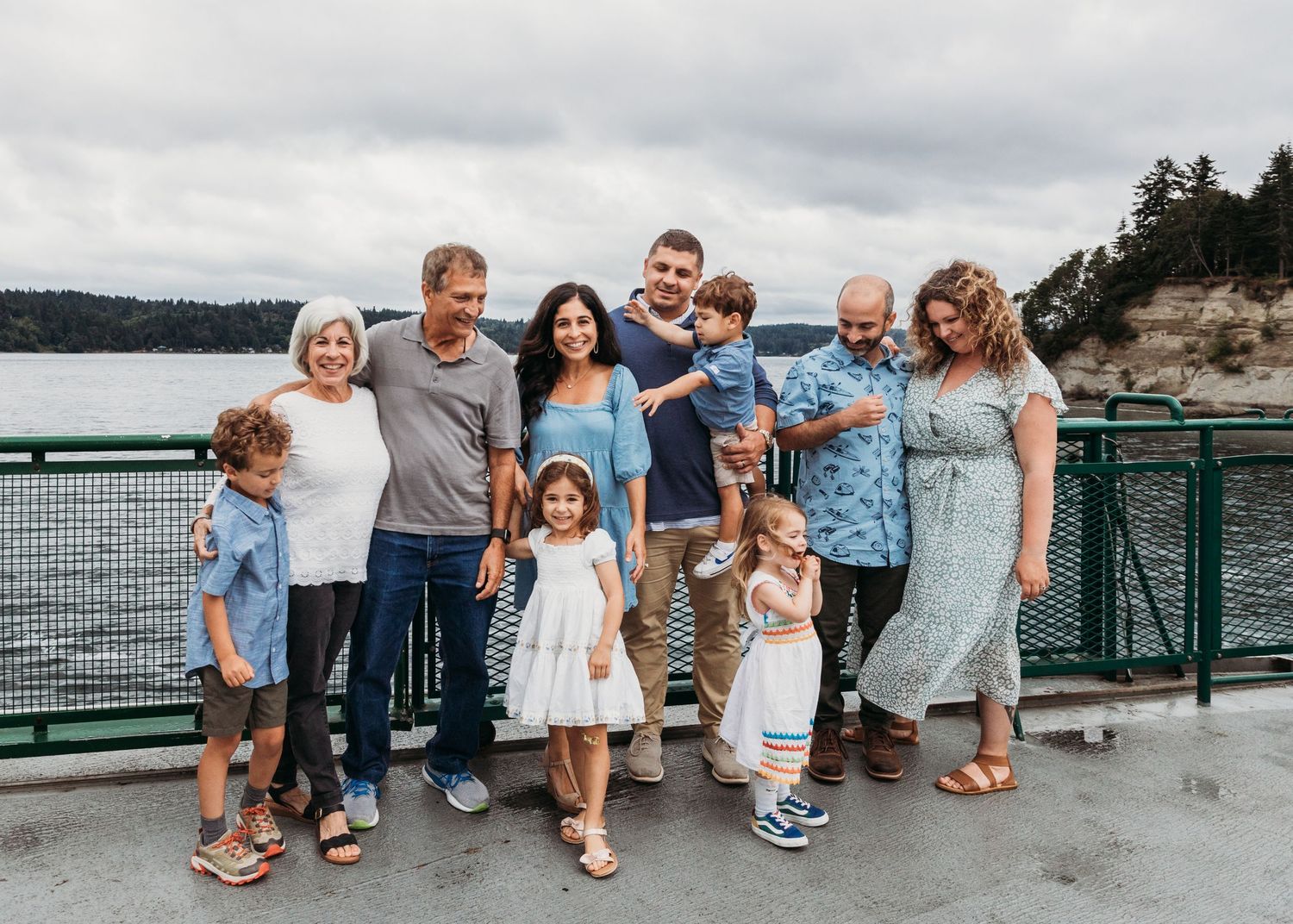 A group poses together on a pier overlooking water on an overcast day.