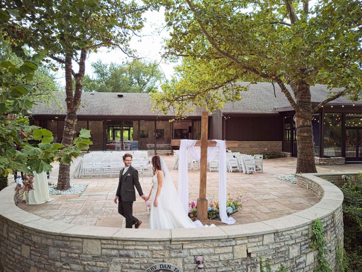 Bride and groom holding hands on a stone patio at the Darby House