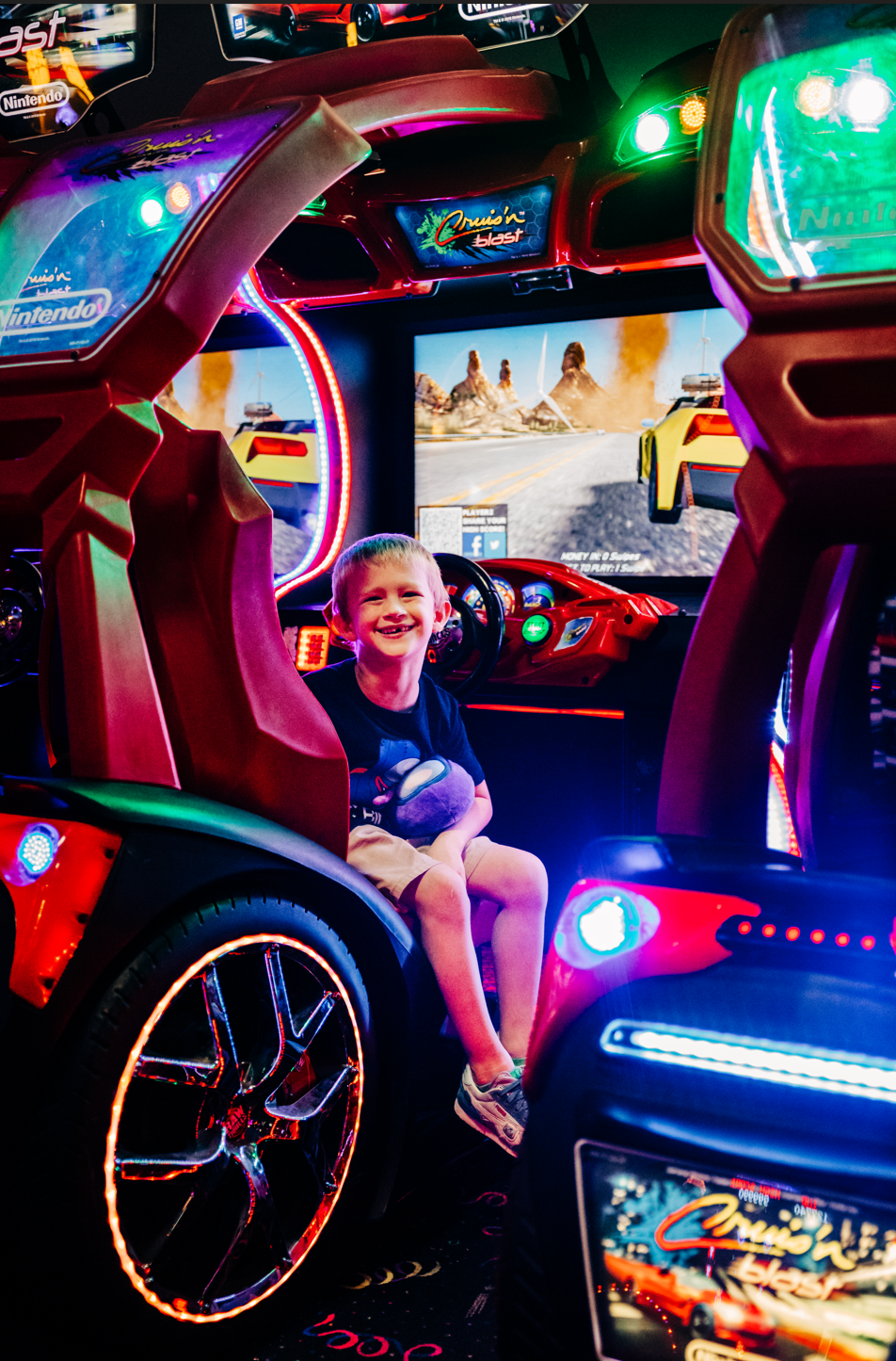 Arcade birthday photos in Lake Worth Beach of a smiling boy inside a colorful racing game at Fun Depot.