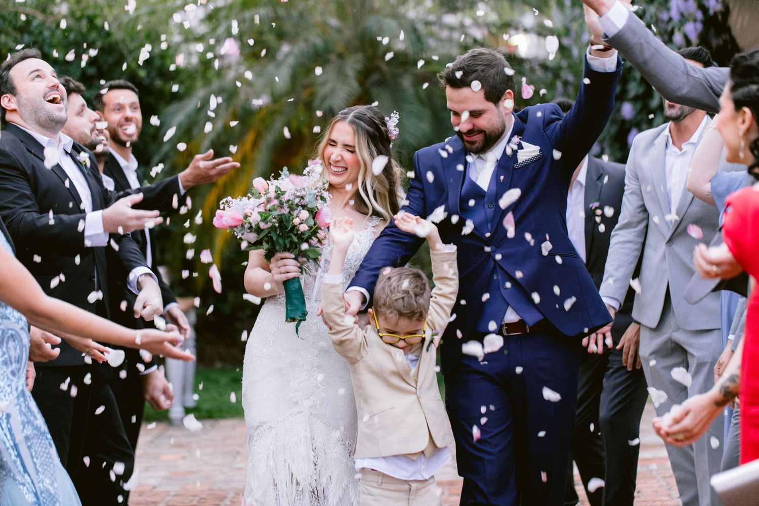 Wedding guests celebrate by throwing confetti during an outdoor celebration.