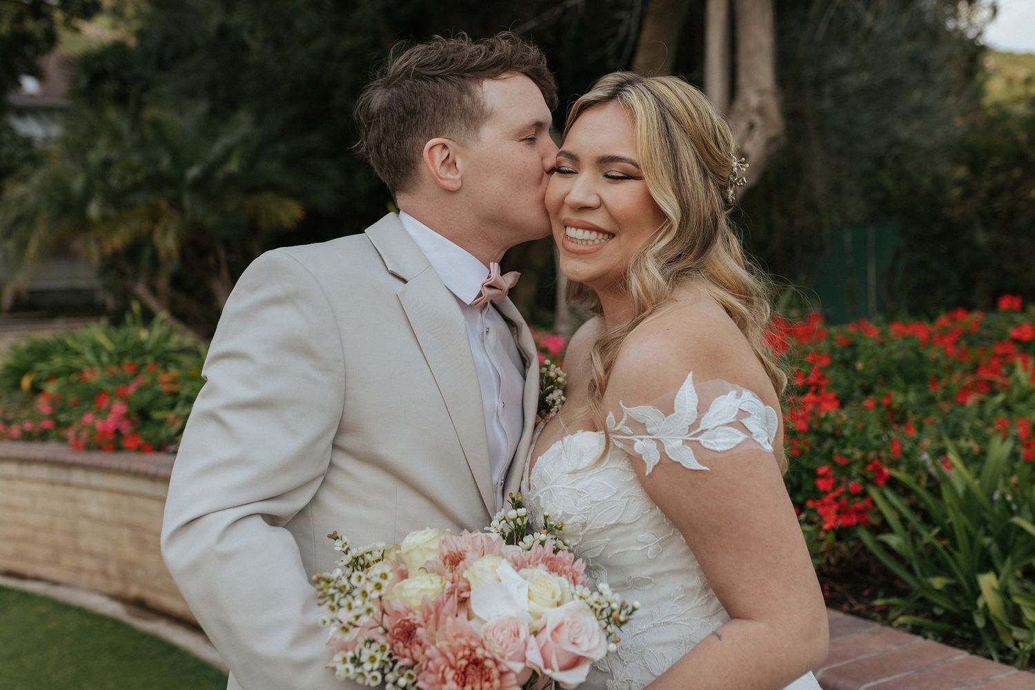 A couple shares a tender moment in a garden with colorful flowers in the background at Singing Hills Golf Resort.