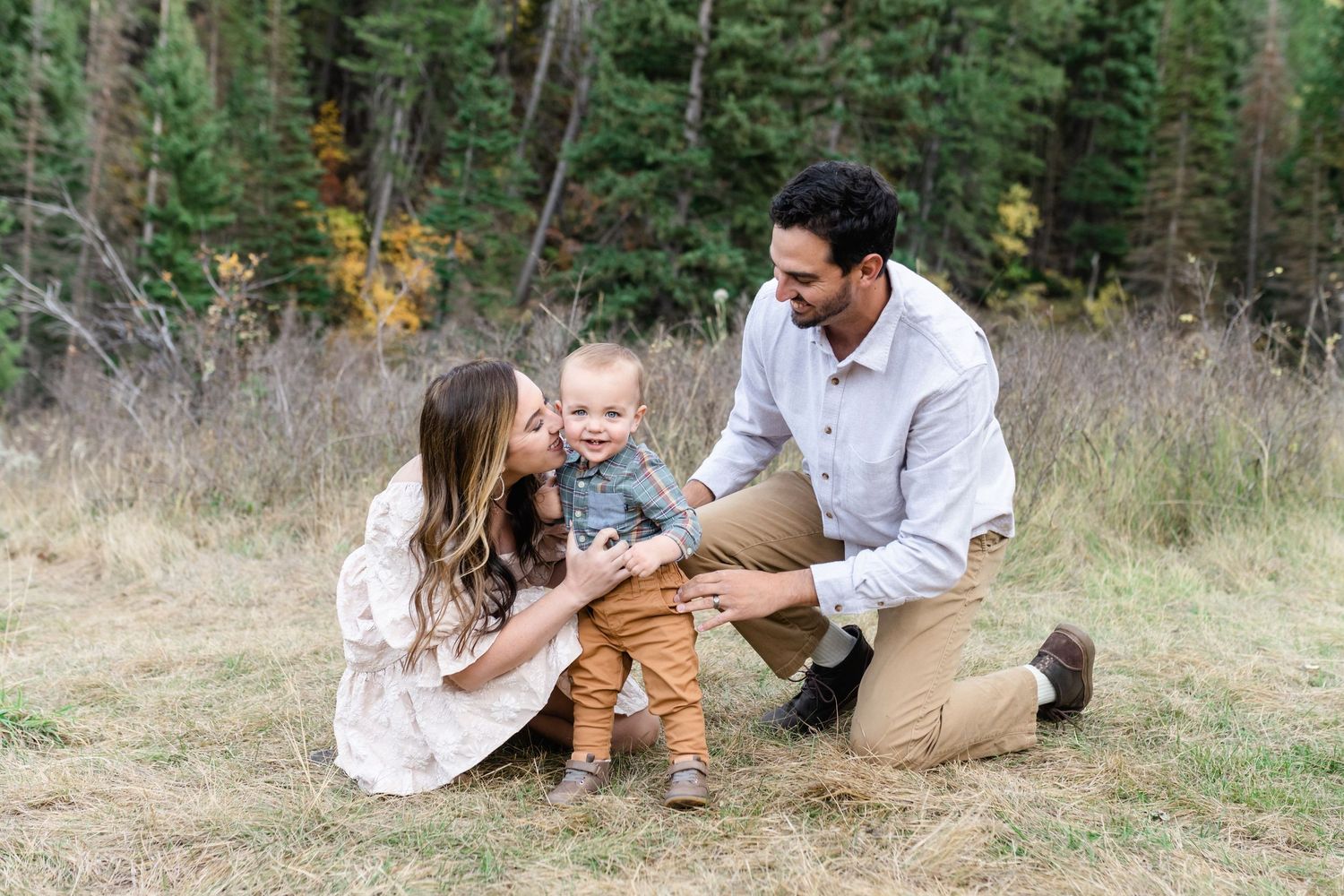 Family enjoying casual moments together in grassy mountain meadow.