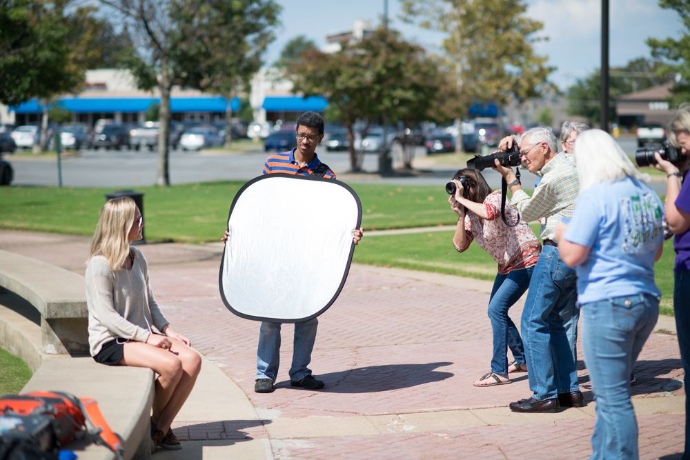 Photography class led by Alex Kent and Jeremy Smith. Group of students taking photos of blonde model sitting outdoors.