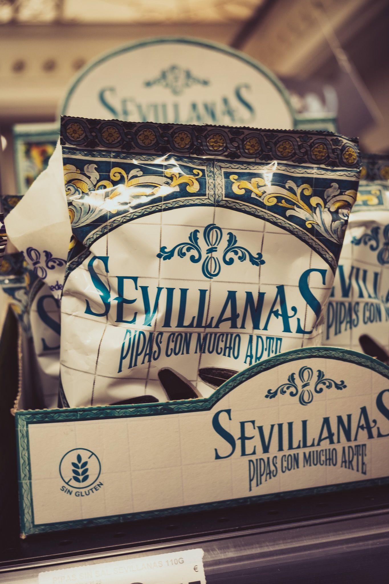 Sevillanas branded sunflower seed snack packets displayed in a shop in Seville, Spain.