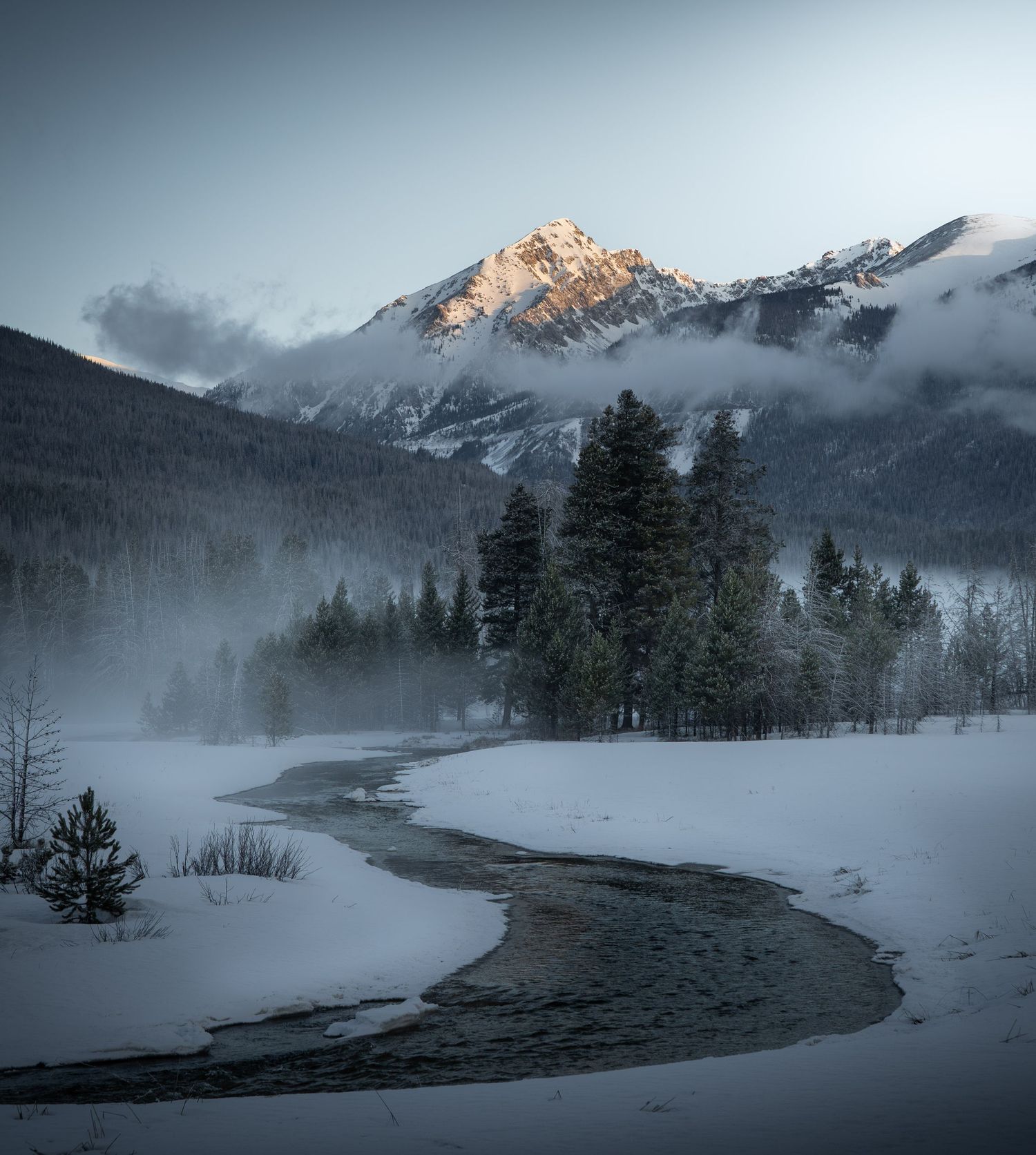 A snowy peak towering above a meandering creek scene in Rocky Mountain National Park, Colorado.