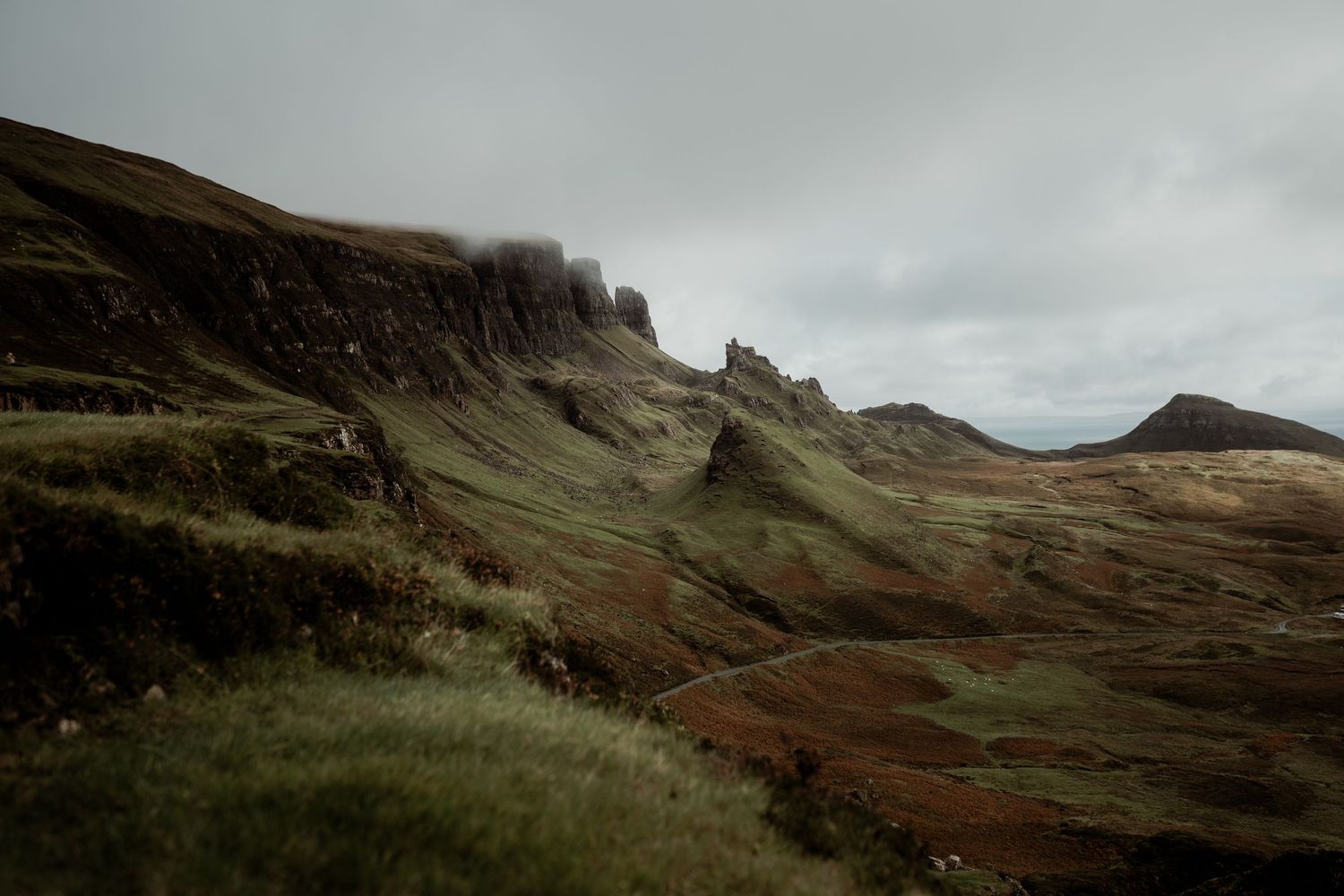 Moody aerial view of the Quiraing on Isle of Skye, Scotland, featuring dramatic green cliffs and misty overcast skies.