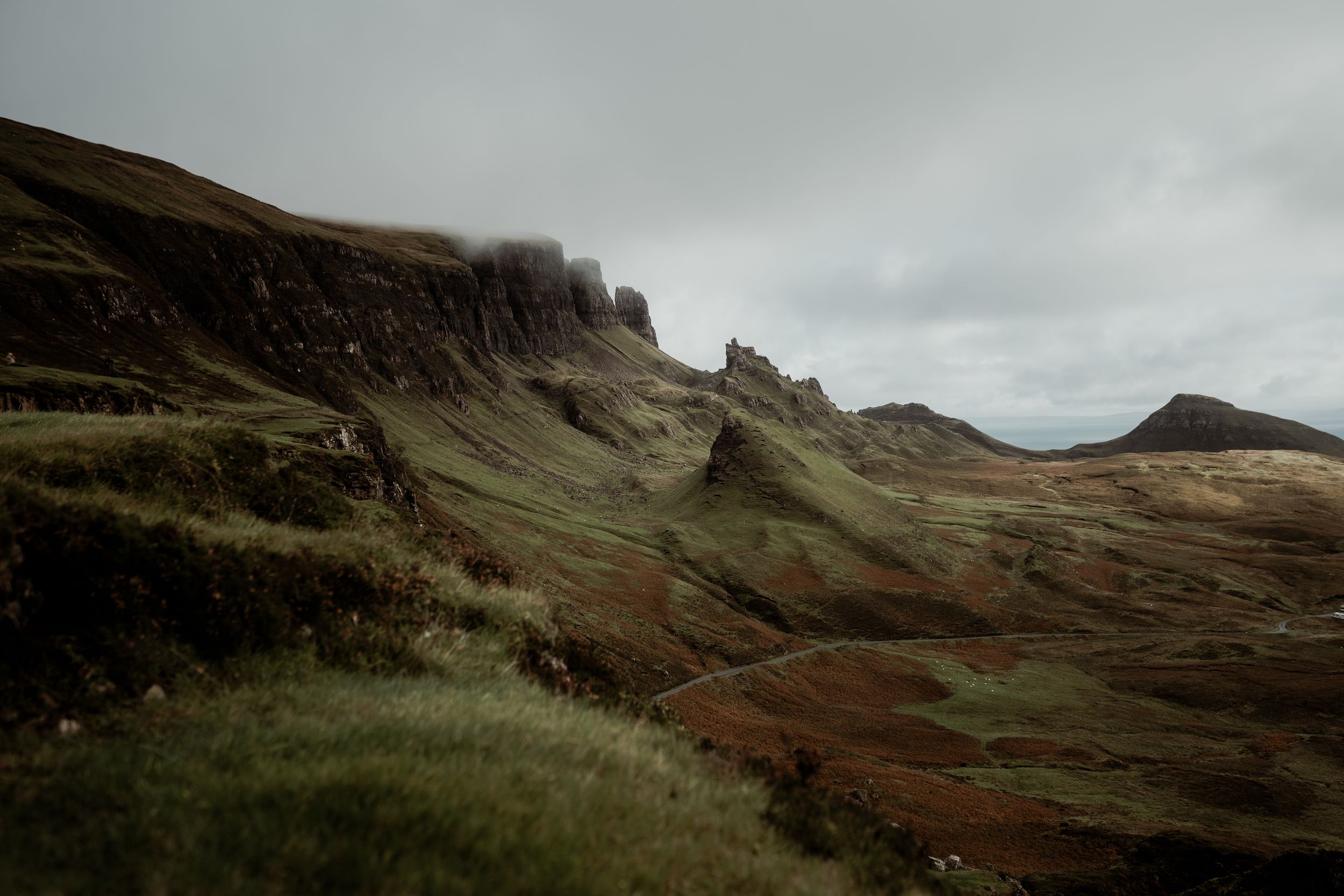 Moody aerial view of the Quiraing on Isle of Skye, Scotland, featuring dramatic green cliffs and misty overcast skies.