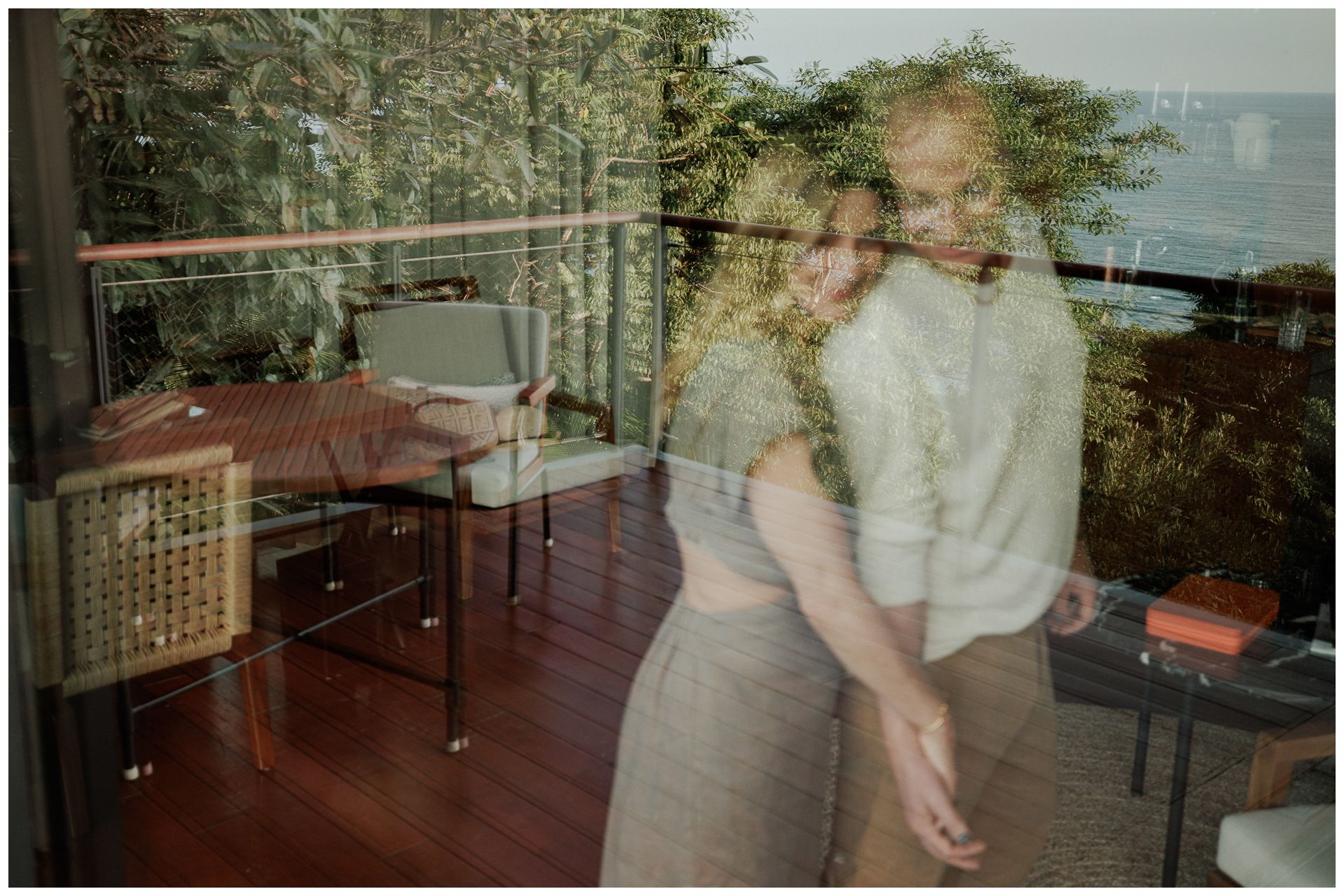 One & Only Mandarina Couple Photographer capturing partners dancing and embracing through a glass reflection with lush tropical greenery.