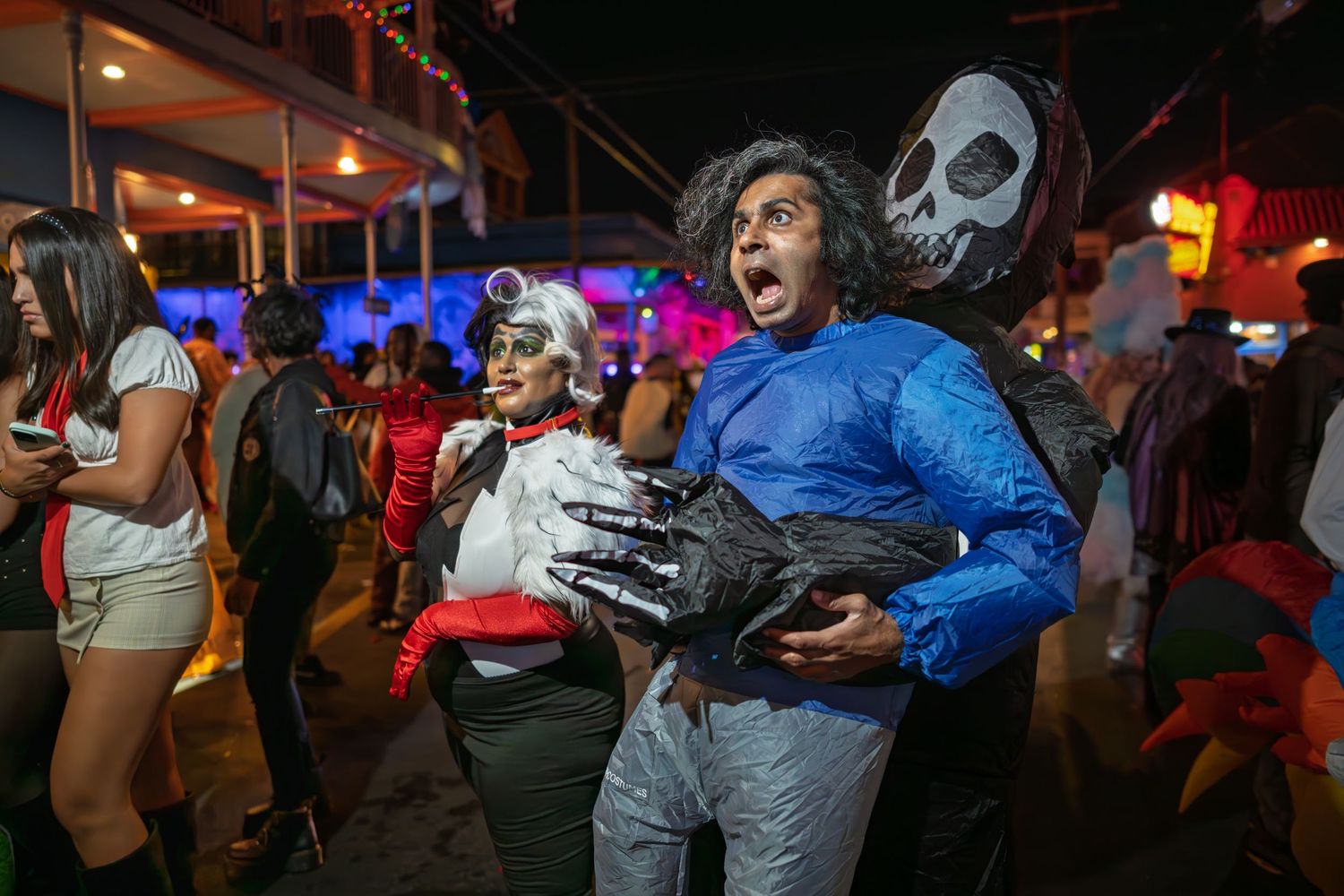 Group of adults in Halloween costumes celebrating outdoors at night, including Harley Quinn and sci-fi characters.