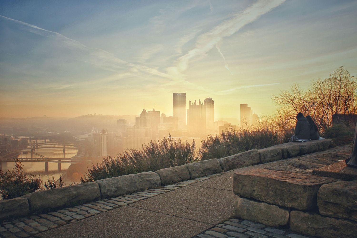 Cityscape of Pittsburgh skyline at sunrise with morning fog rolling over downtown and bridges across the river.