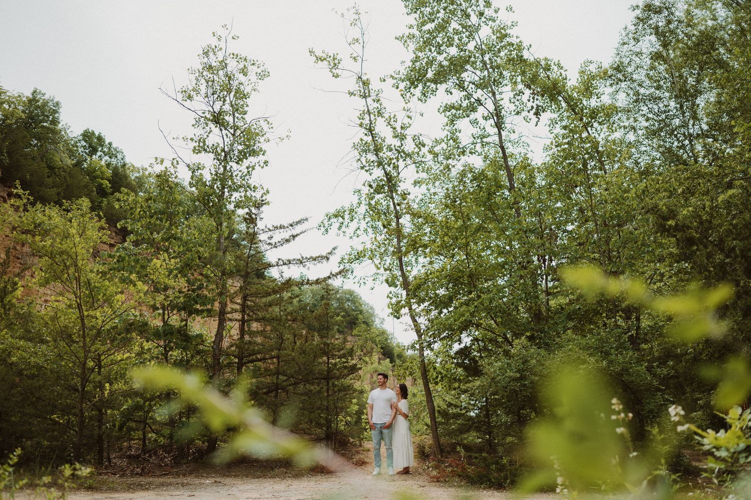 A scenic forest path with flowering trees and greenery creates a romantic natural setting.