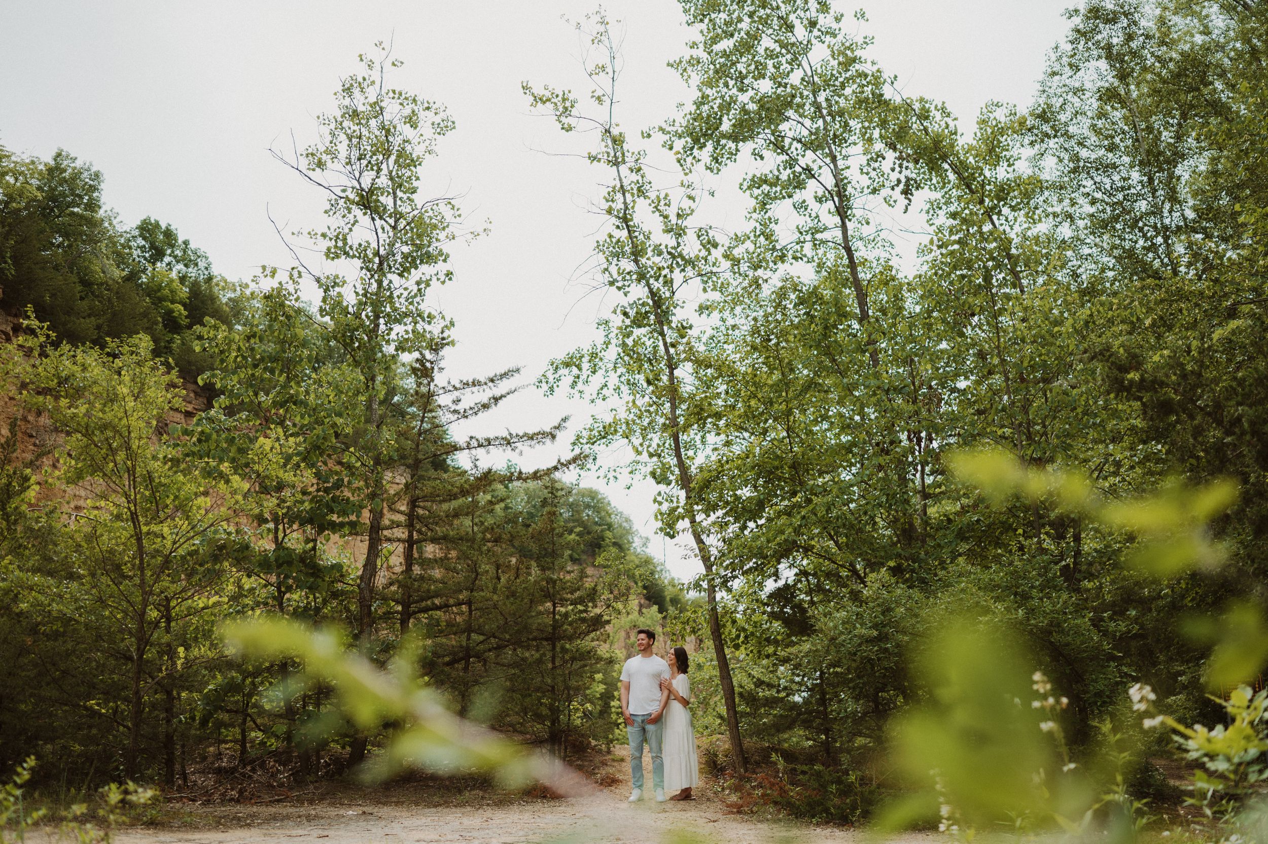 A scenic forest path with flowering trees and greenery creates a romantic natural setting.