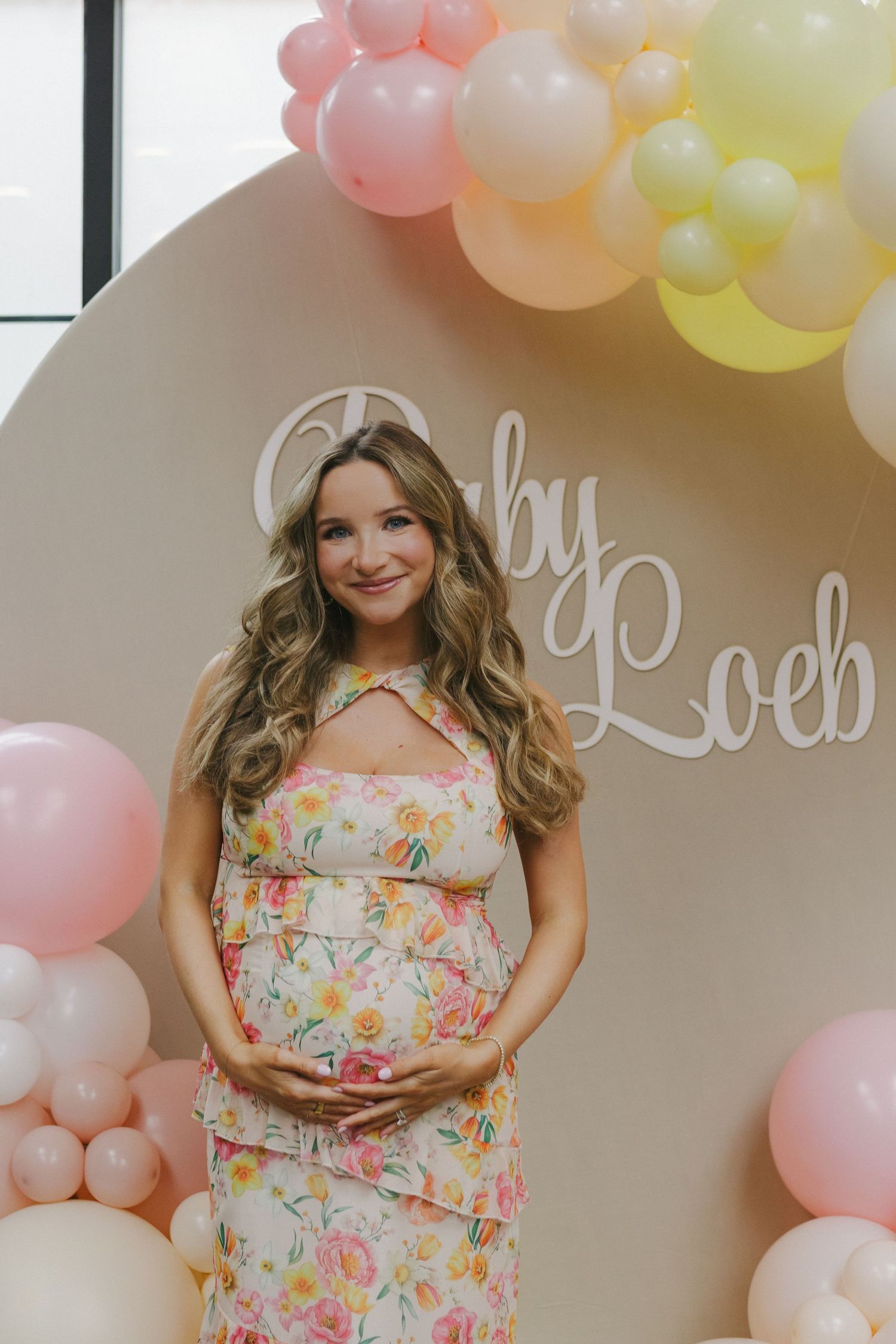 Mom-to-be glowing in a pink floral dress at Brooklyn Winery, captured by NYC baby shower photographer Paula Brearley