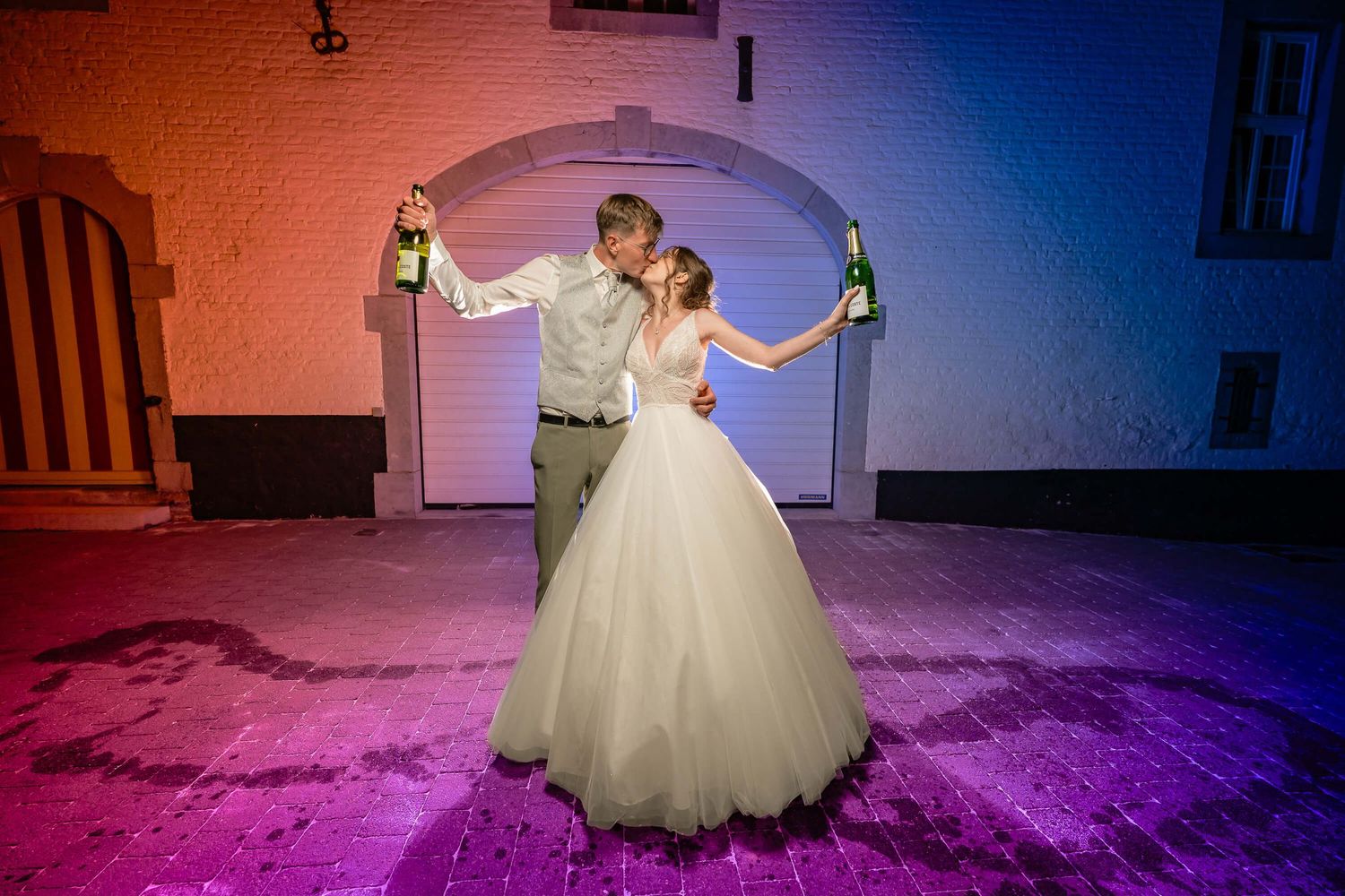 A couple sharing their first dance at a wedding under dramatic pink and purple lighting in an elegant venue.