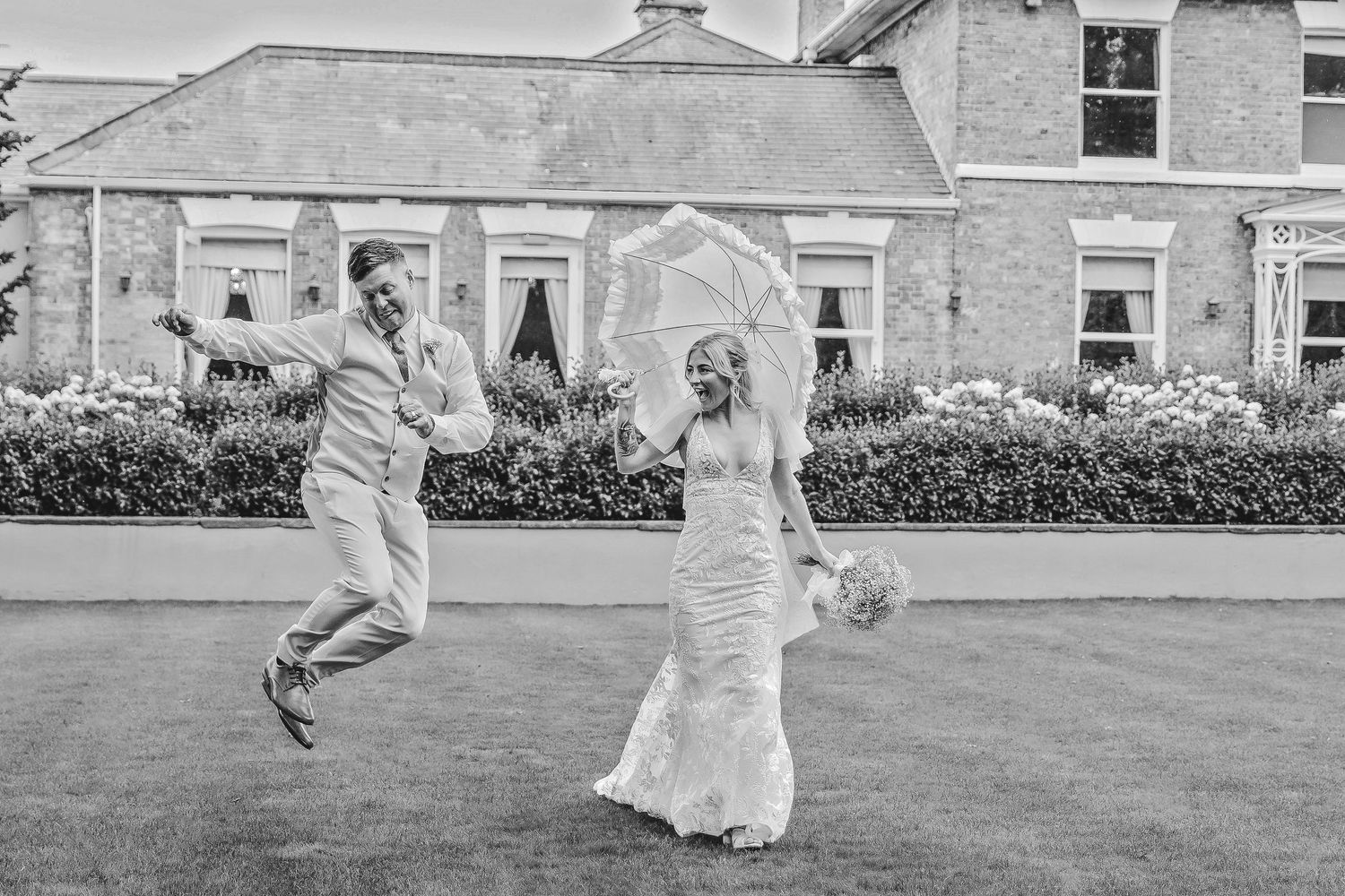 Wedding couple running playfully on grass outside historic building. Photographer. Hull. East Yorkshire. Photography