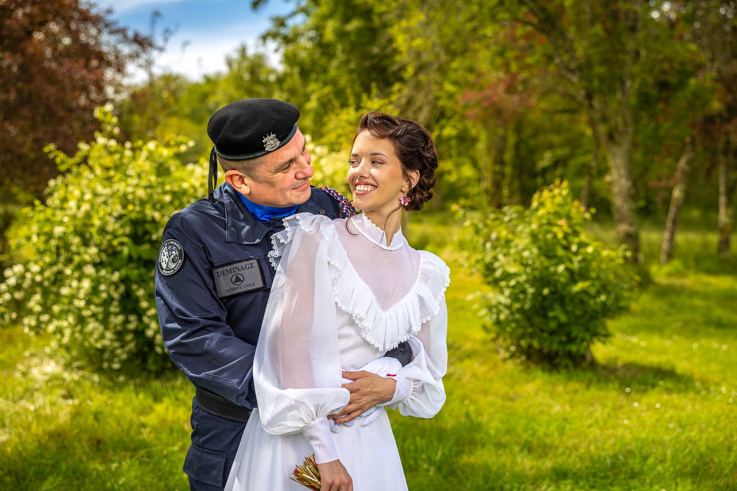 A romantic embrace between newlyweds in a lush green garden setting.